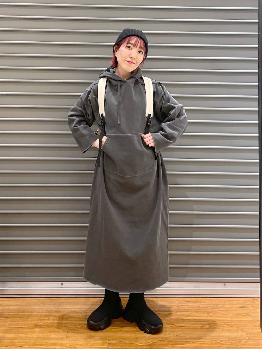 ホワイト系のバックパック/リュック、ブラック系のブーツ、グレー系のワンピースを着用したレディースの春コーディネートの2枚目の写真