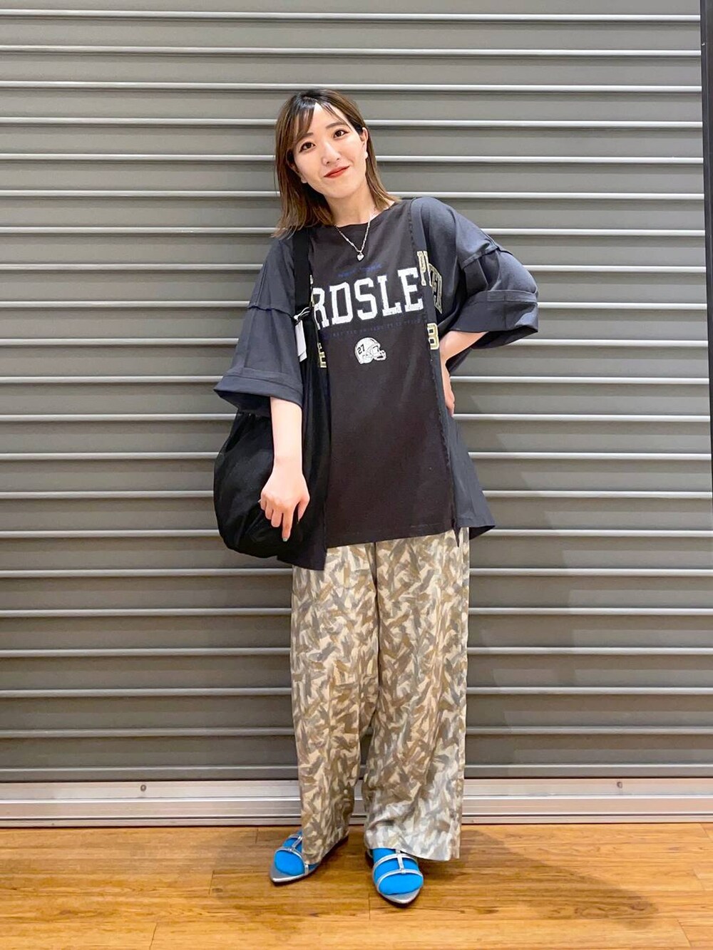 ブラック系のショルダーバッグ、ブラック系のTシャツ/カットソー、グレー系のその他パンツを着用したレディースの春コーディネートの2枚目の写真