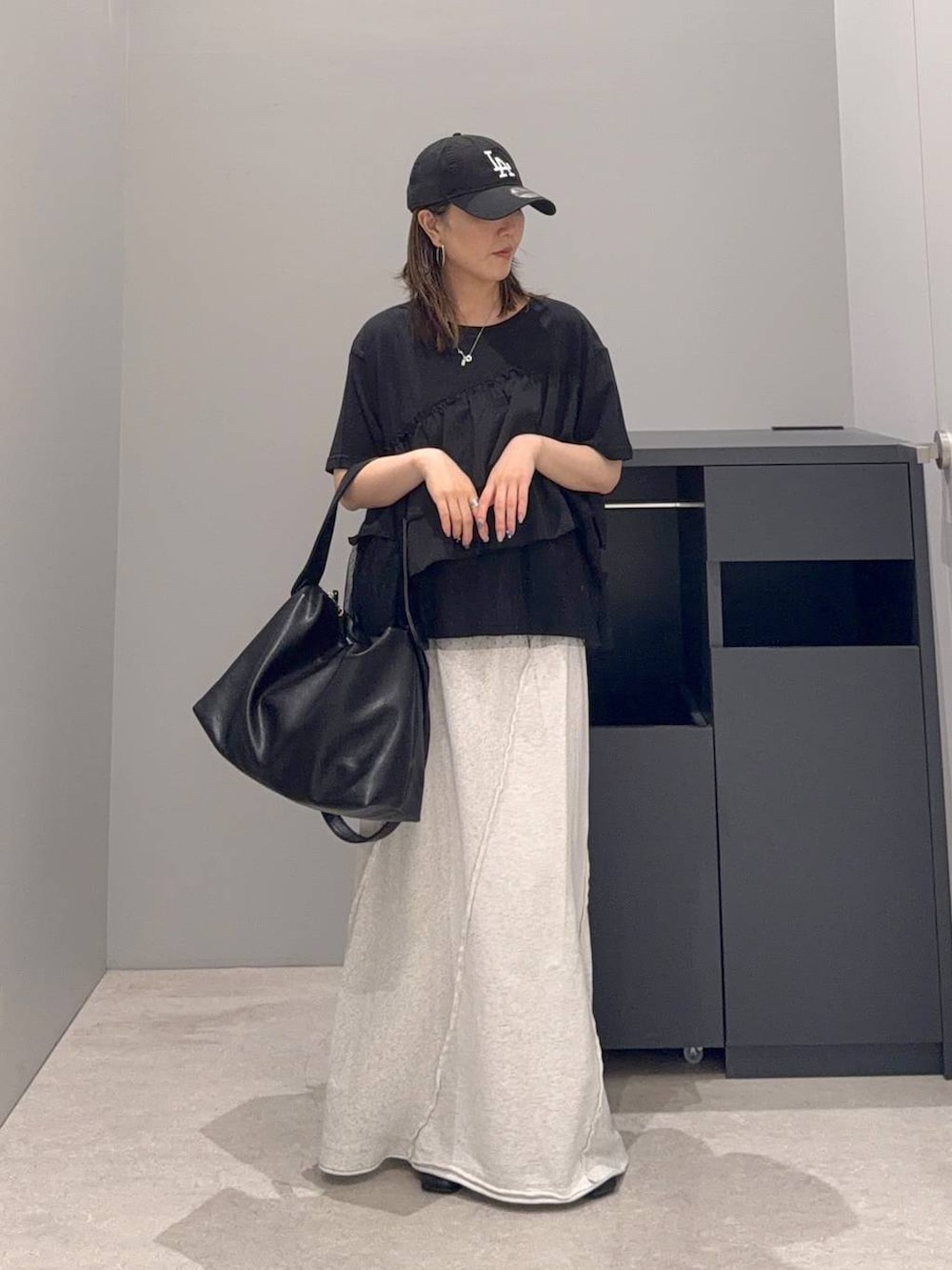 グレー系のスカート、ブラック系のショルダーバッグ、ブラック系のTシャツ/カットソーを着用したレディースの夏コーディネートの2枚目の写真