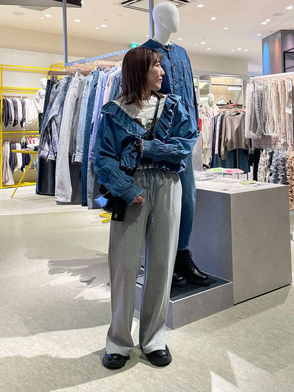 グレー系のスウェットパンツ、ブルー系のシャツ/ブラウス、ブラック系のショルダーバッグを着用したレディースの冬コーディネートの3枚目の写真