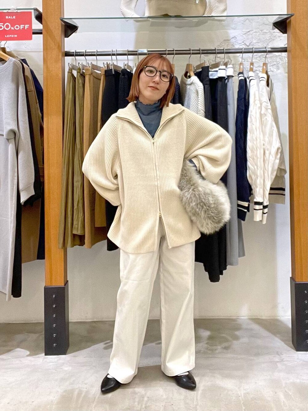 グレー系のハンドバッグ、ホワイト系のニット/セーター、ブラック系のパンプスを着用したレディースの冬コーディネートの3枚目の写真