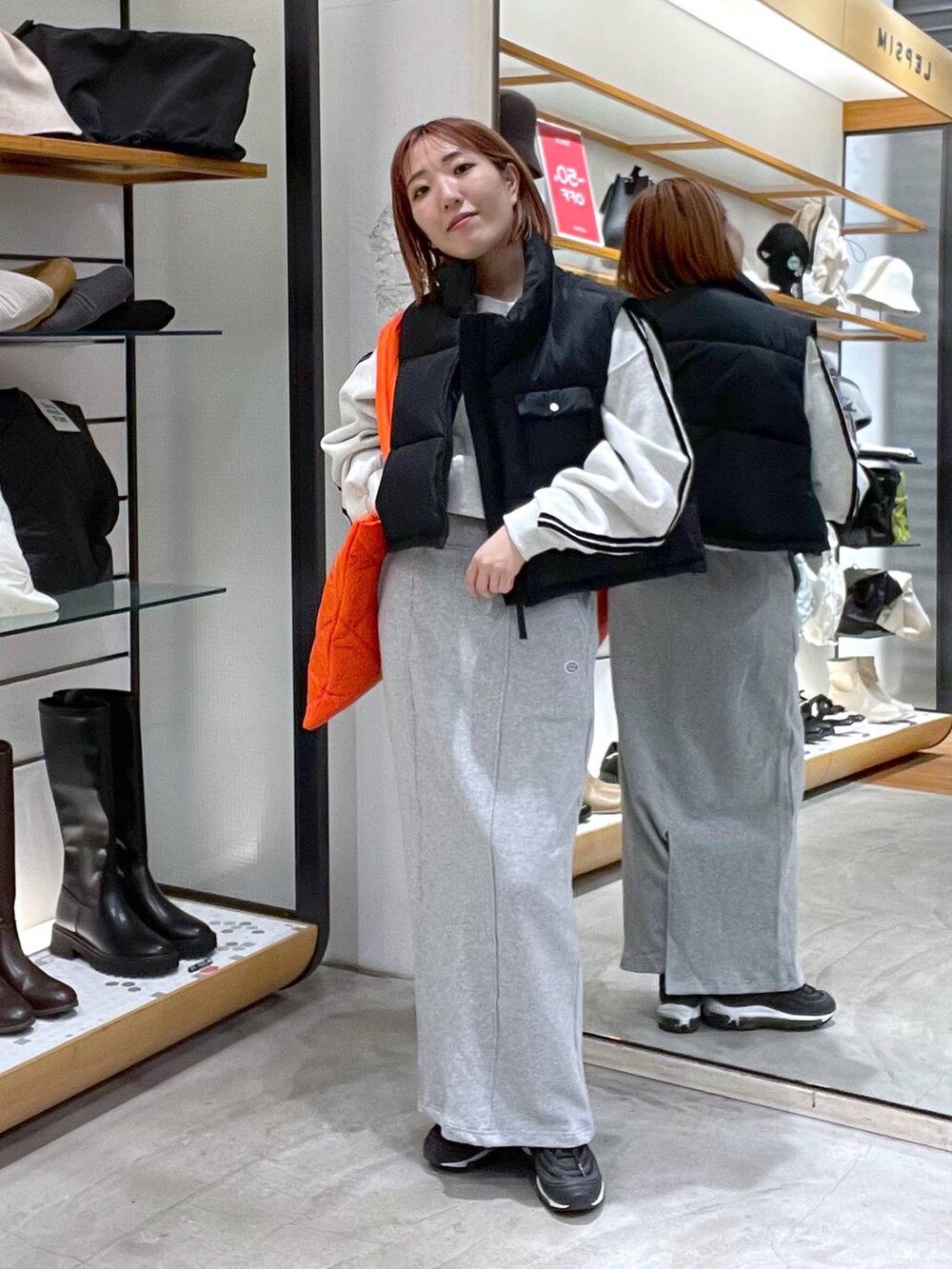 オレンジ系のトートバッグ、グレー系のTシャツ/カットソー、ブラック系のベストを着用したレディースの冬コーディネートの3枚目の写真