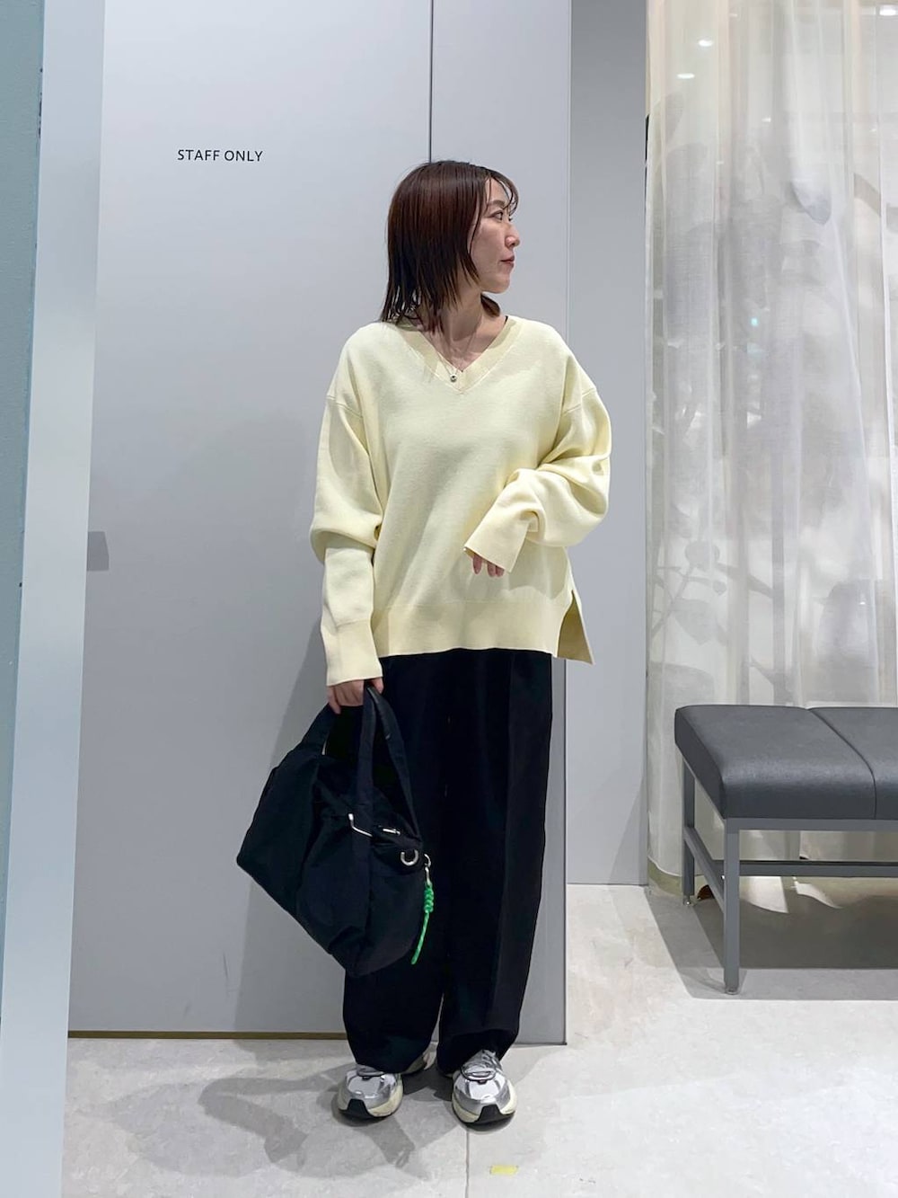 ブラック系のトートバッグ、イエロー系のニット/セーターを着用したレディースの冬コーディネートの2枚目の写真