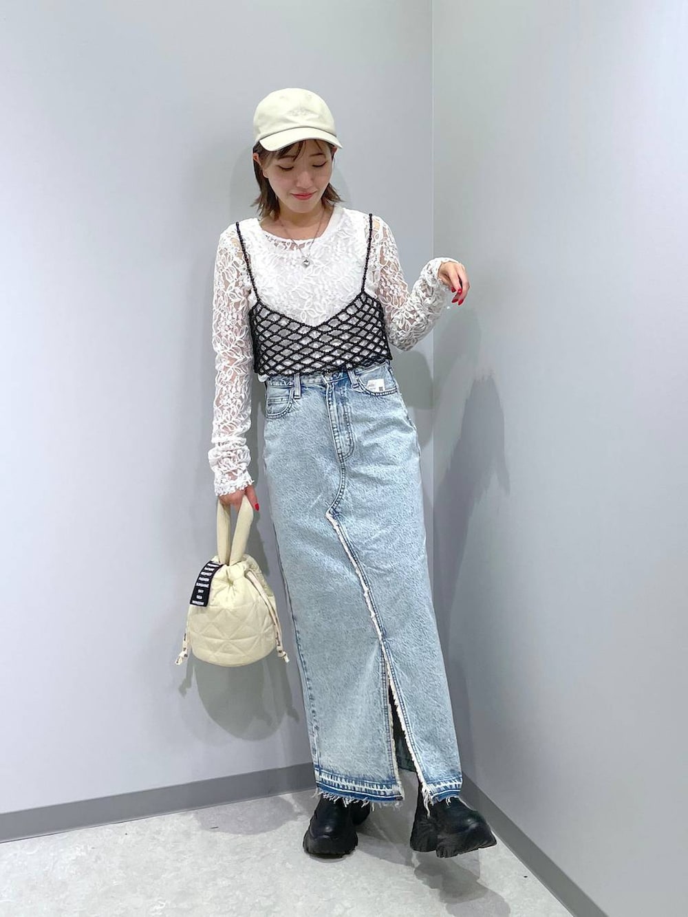 ブラック系のベスト、ブルー系のスカート、ホワイト系のTシャツ/カットソーを着用したレディースの秋コーディネートの2枚目の写真