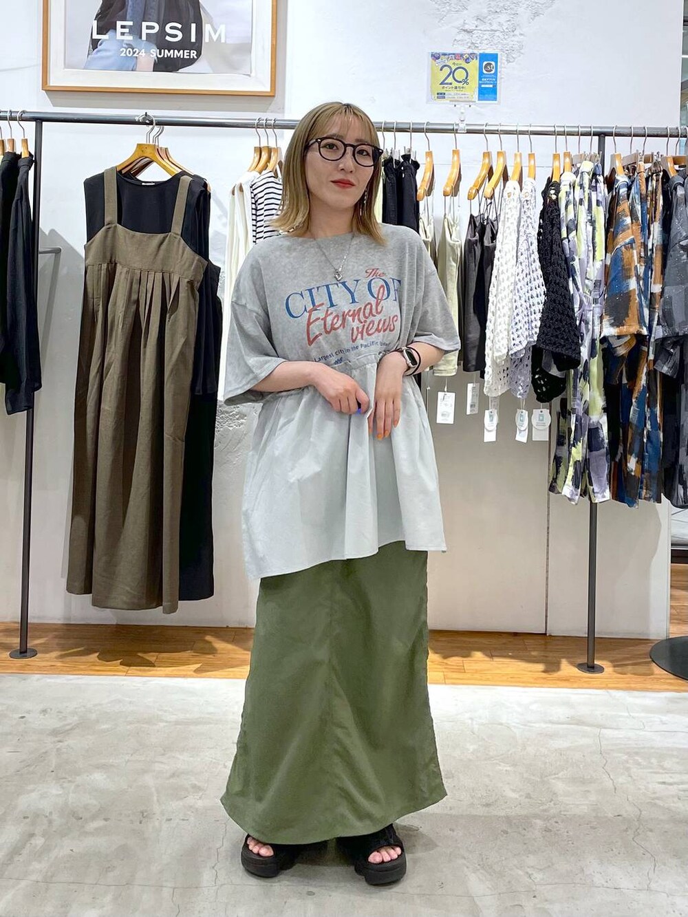 グリーン系のスカート、グリーン系のショルダーバッグ、ベージュ系のTシャツ/カットソーを着用したレディースの春コーディネートの3枚目の写真