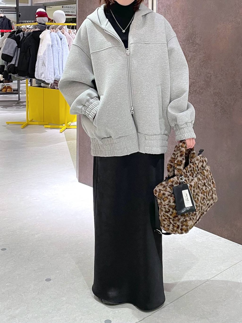 ブラック系のスカート、ブラック系のニット/セーター、グレー系のパーカーを着用したレディースの冬コーディネートの3枚目の写真