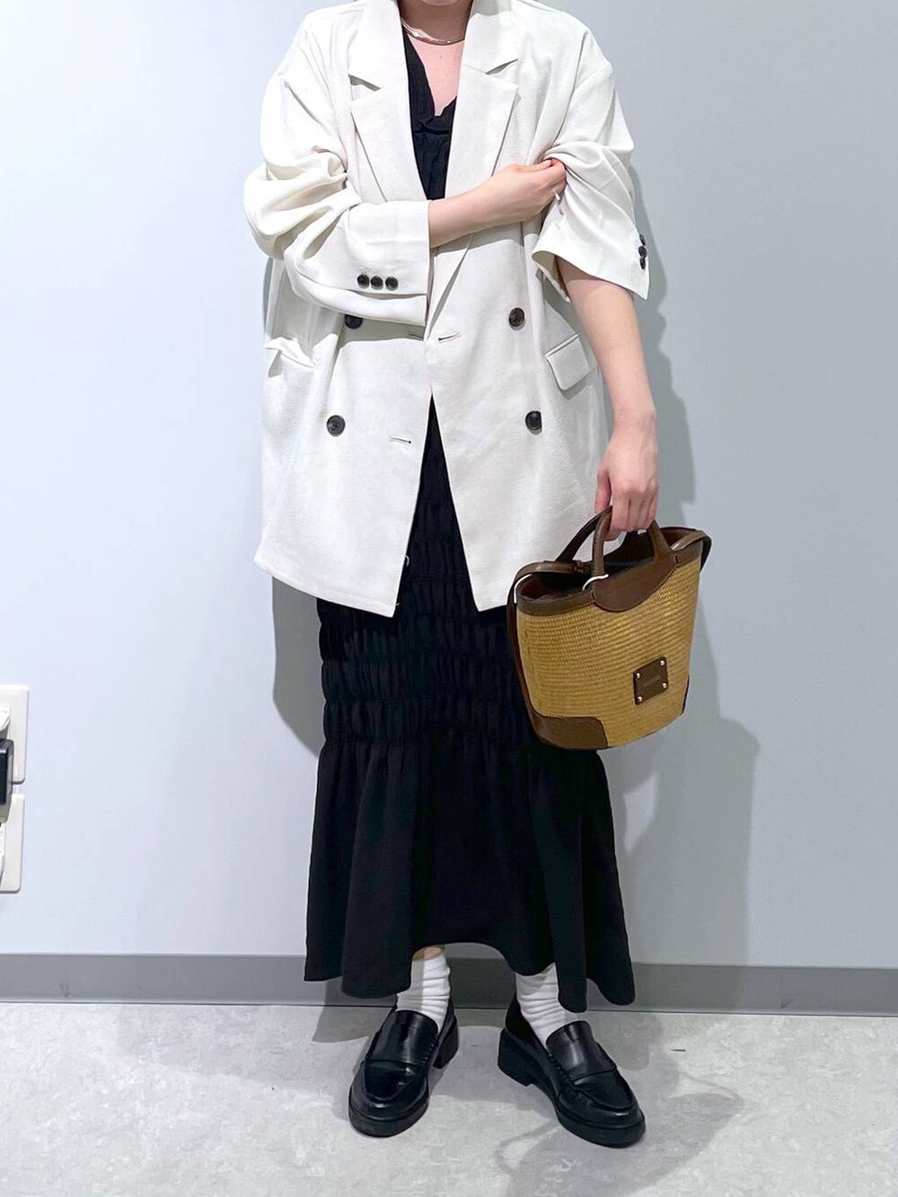 ホワイト系のテーラードジャケット、ブラウン系のショルダーバッグ、ブラック系のワンピースを着用したレディースの春コーディネートの4枚目の写真