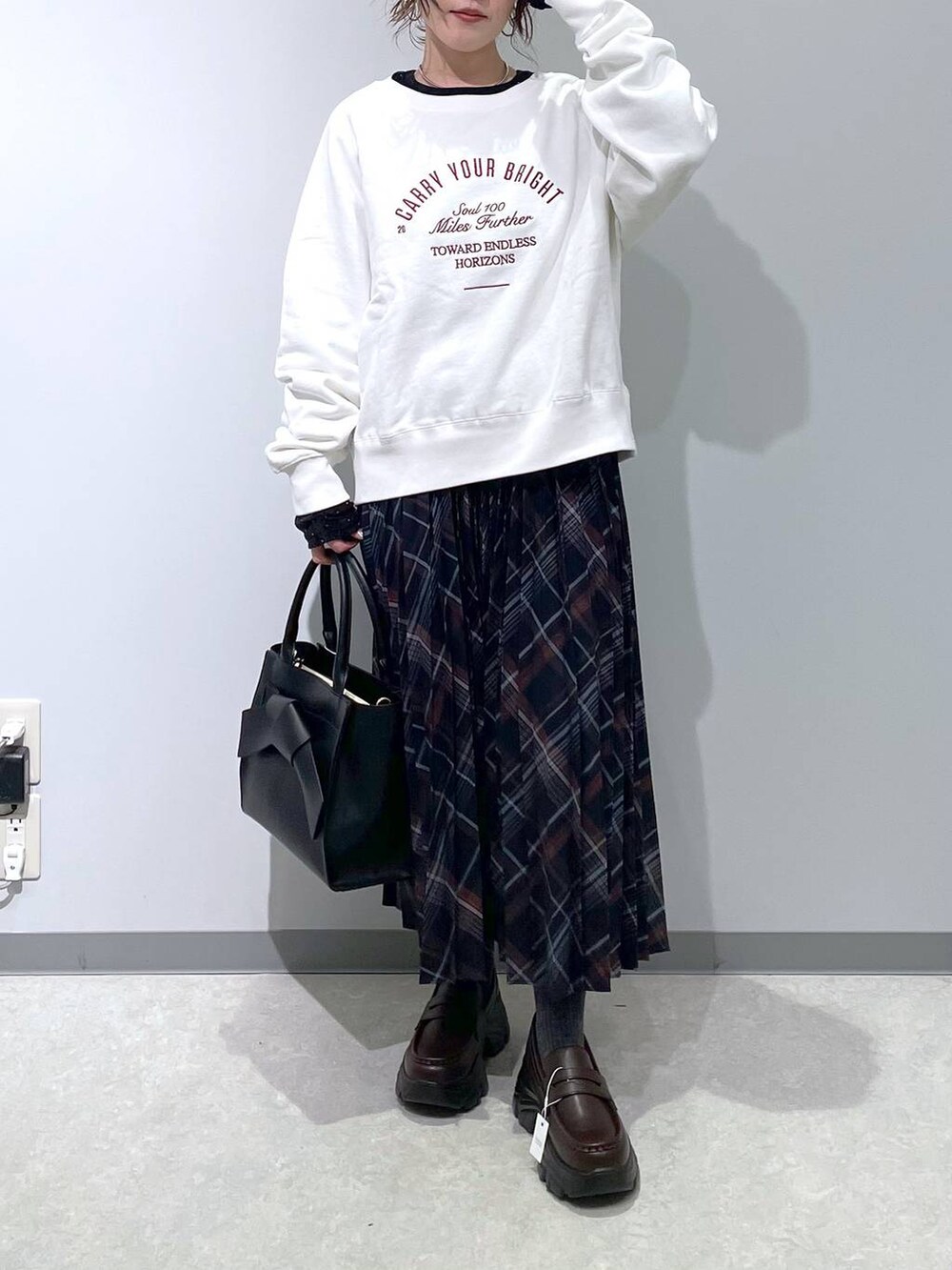 ブルー系のスカート、ブラック系のハンドバッグ、ブラック系のTシャツ/カットソーを着用したレディースの冬コーディネートの3枚目の写真