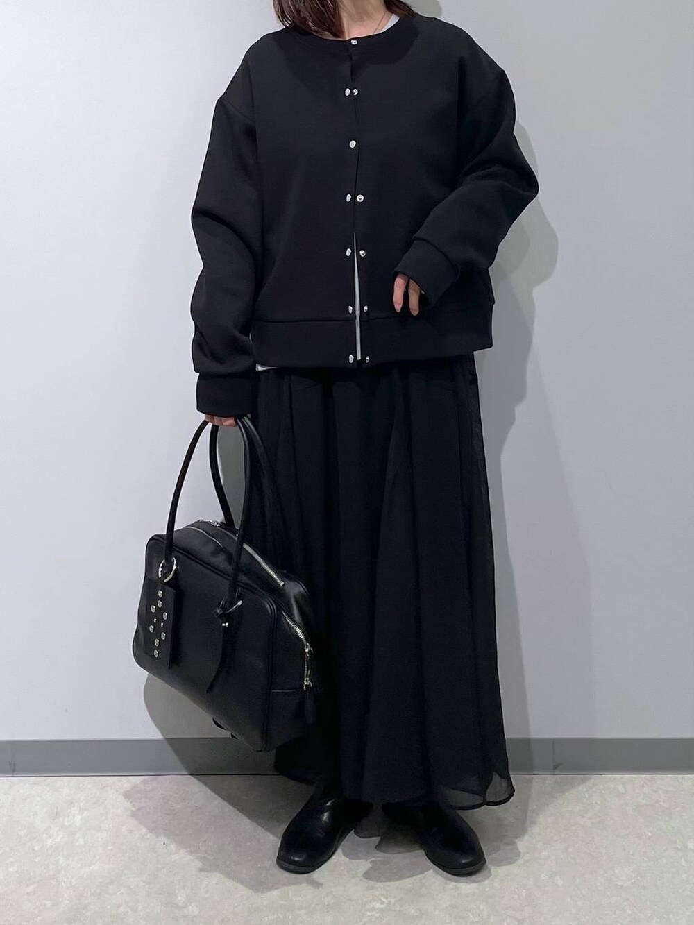 グレー系のニット/セーター、ブラック系のカーディガン/ボレロ、ブラック系のボストンバッグを着用したレディースの春コーディネートの3枚目の写真