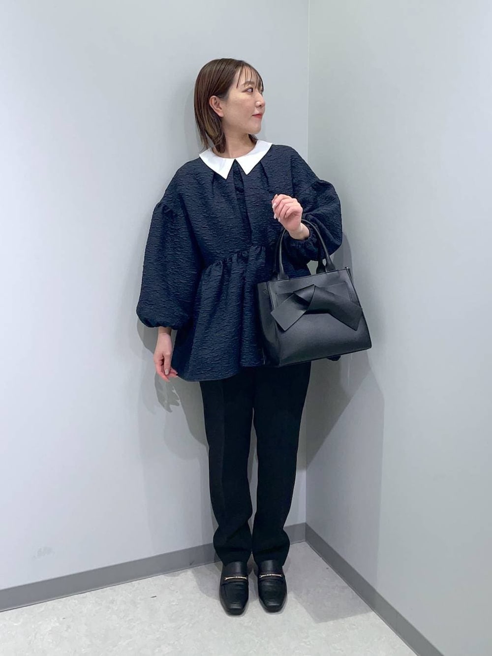 ブラック系のローファー、ブラック系のハンドバッグ、ブルー系のスーツセットを着用したレディースの冬コーディネートの3枚目の写真