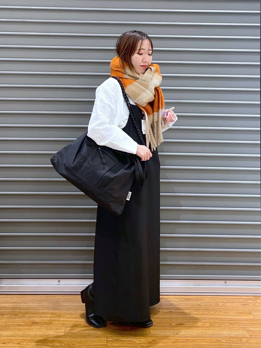 ブラック系のワンピース、ブラック系のショルダーバッグ、ホワイト系のTシャツ/カットソーを着用したレディースの冬コーディネートの2枚目の写真