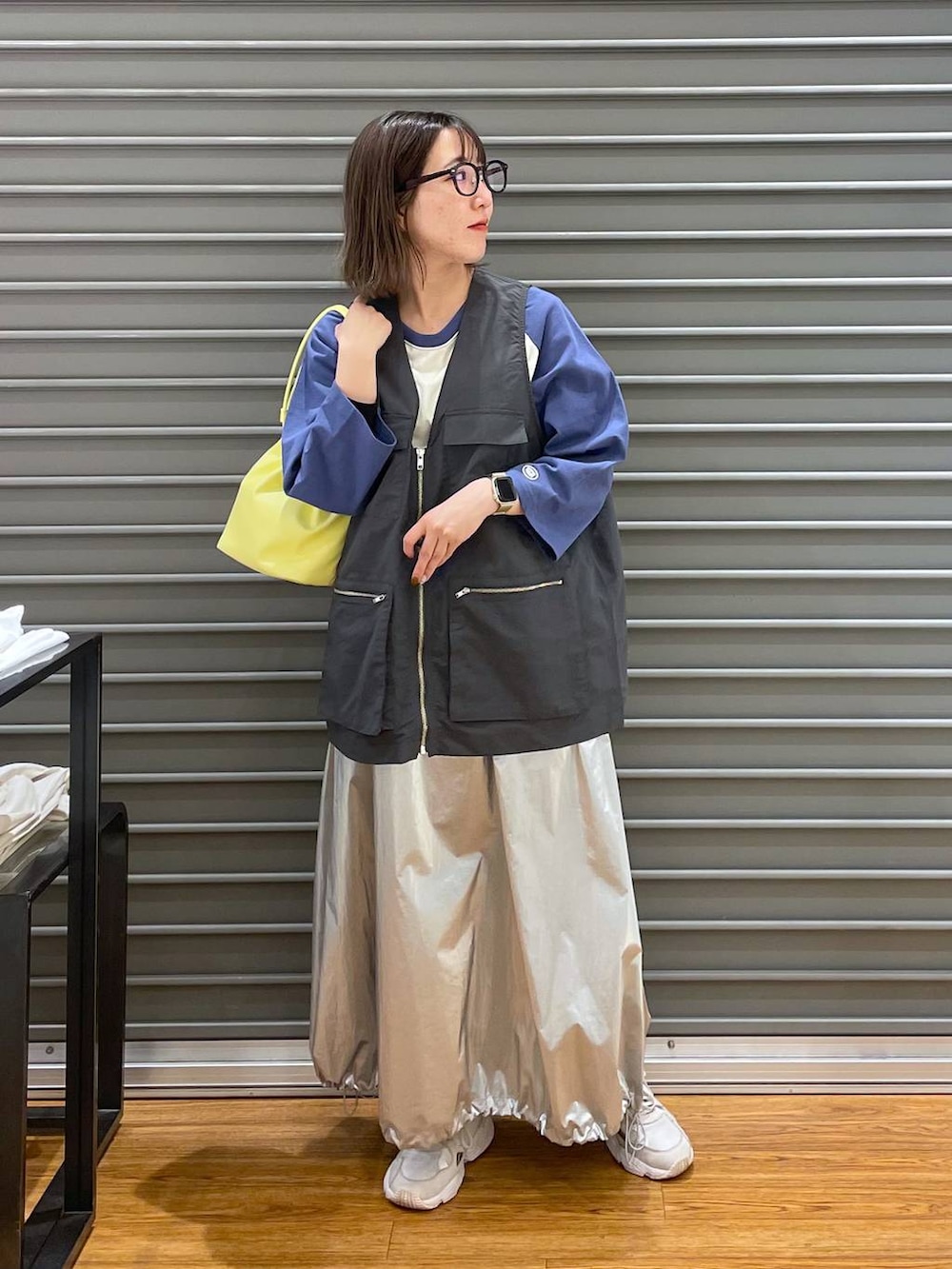 イエロー系のショルダーバッグ、ブルー系のTシャツ/カットソー、シルバー系のスカートを着用したレディースの春コーディネートの2枚目の写真