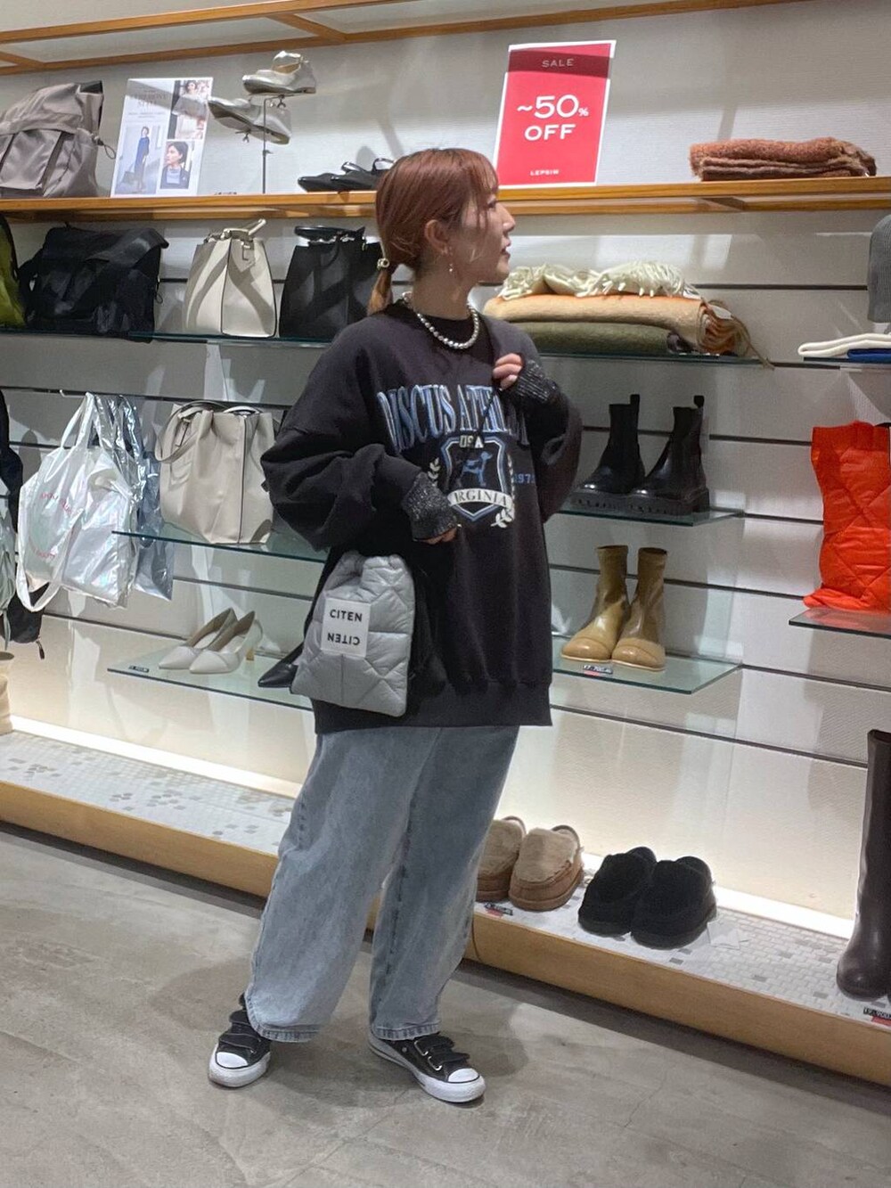 グレー系のスウェット、ブルー系のデニムパンツを着用したレディースの冬コーディネートの3枚目の写真