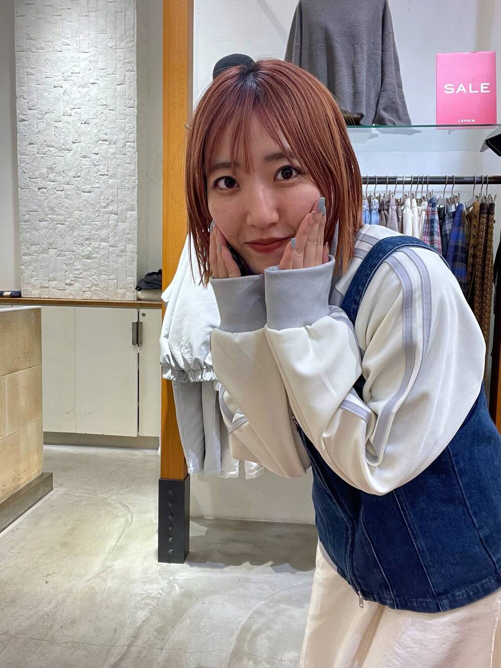 ホワイト系のスカート、ブルー系のベスト、グレー系のジャージを着用したレディースの春コーディネートの4枚目の写真