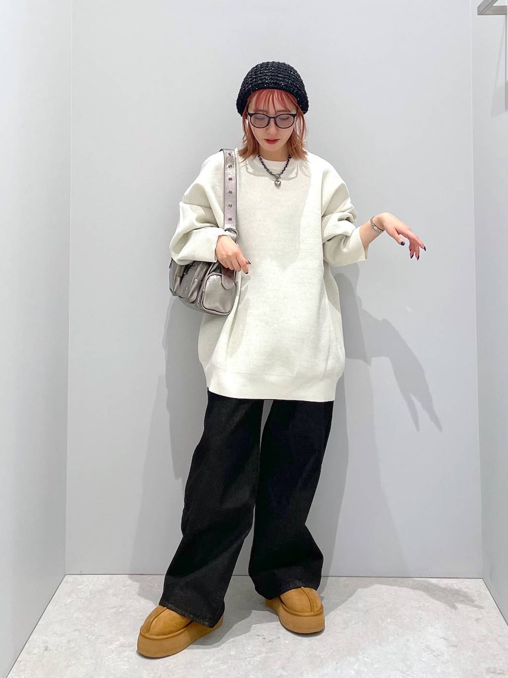 シルバー系のショルダーバッグ、ホワイト系のニット/セーター、ブラック系のデニムパンツを着用したレディースの秋コーディネートの2枚目の写真