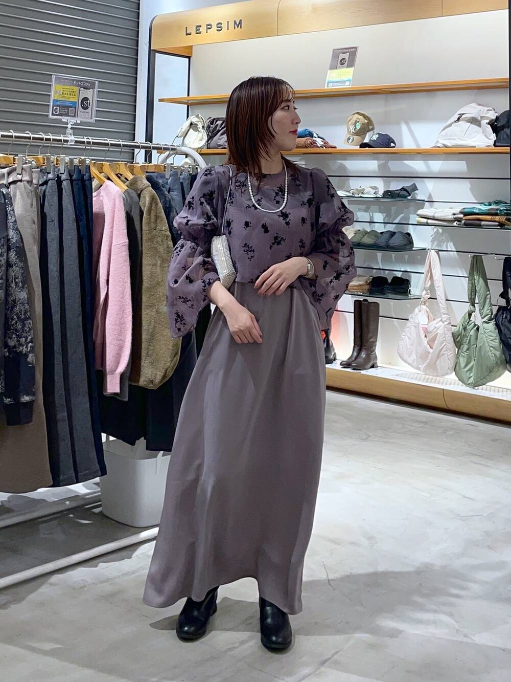 ブラック系のブーツ、ホワイト系のショルダーバッグ、パープル系のワンピースを着用したレディースの冬コーディネートの2枚目の写真