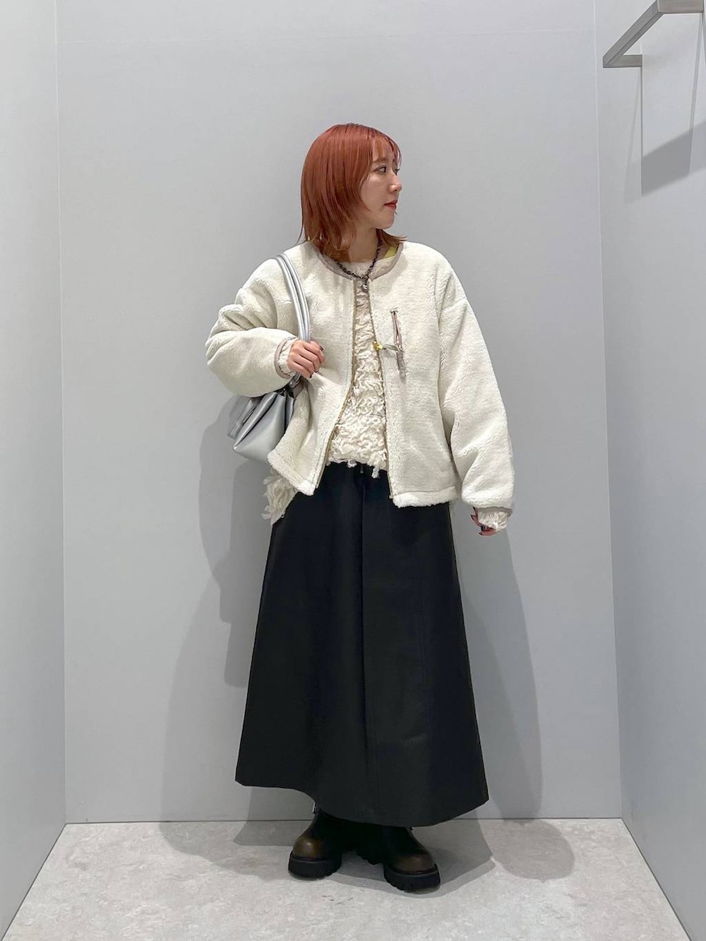 ベージュ系のブルゾン、シルバー系のショルダーバッグ、グリーン系のブーツを着用したレディースの秋コーディネートの2枚目の写真