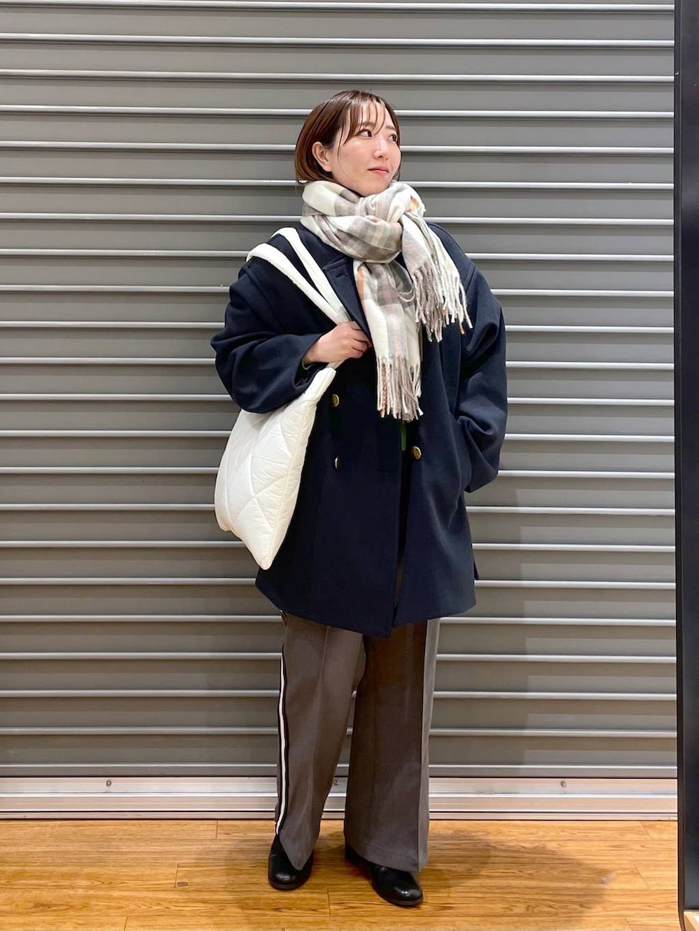 ブラック系のブーツ、ホワイト系のトートバッグ、グレー系のその他パンツを着用したレディースの秋コーディネートの2枚目の写真