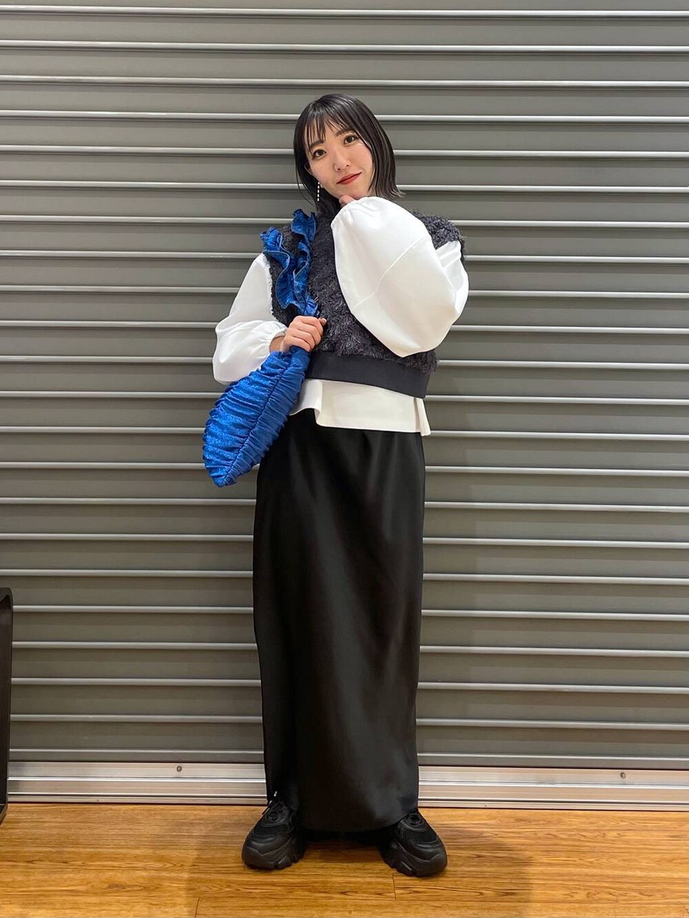 グレー系のベスト、ブラック系のスカート、ホワイト系のTシャツ/カットソーを着用したレディースの春コーディネートの3枚目の写真