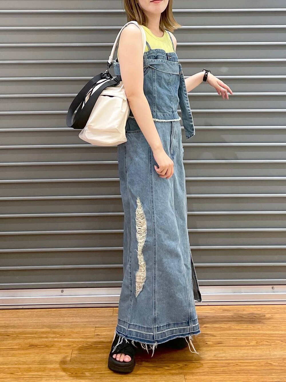 ホワイト系のショルダーバッグ、ブルー系のスカート、ブルー系のベストを着用したレディースの夏コーディネートの2枚目の写真
