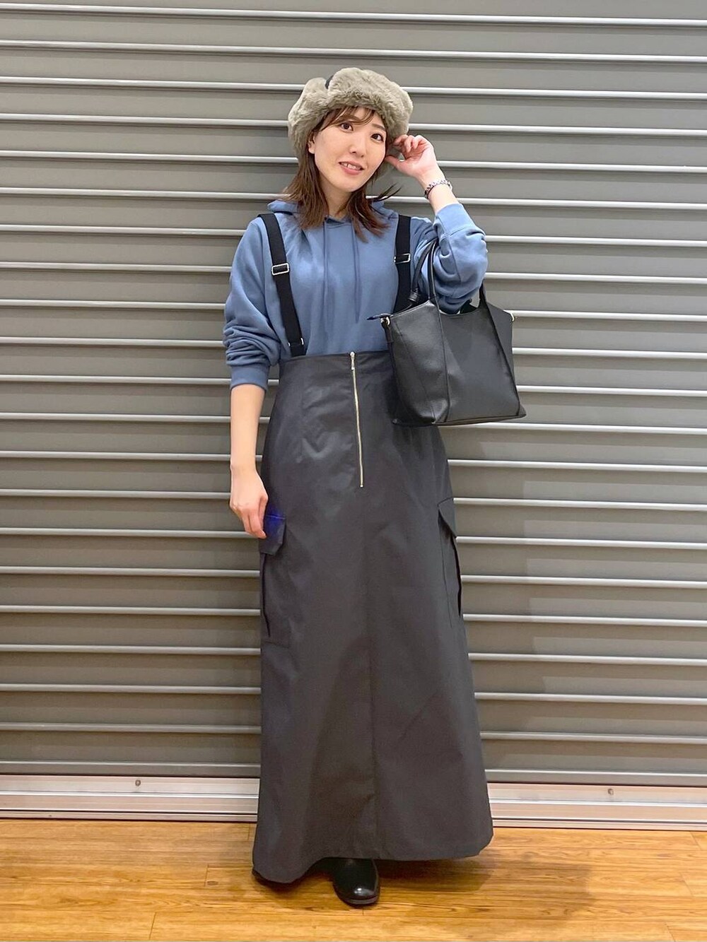 ブラック系のショルダーバッグ、ブルー系のパーカー、ブラウン系のブーツを着用したレディースの冬コーディネートの2枚目の写真