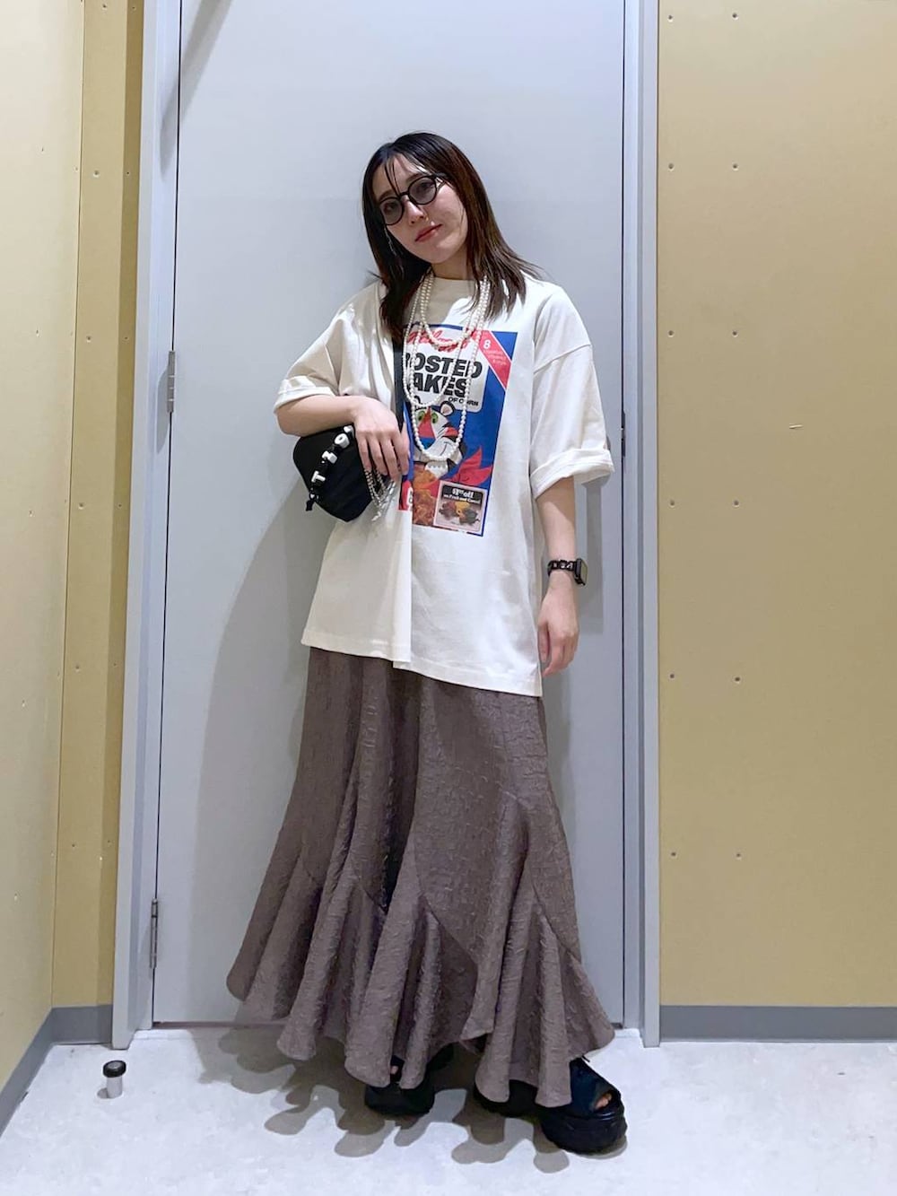 ブラウン系のスカート、ブラック系のトートバッグ、ブラック系のサンダルを着用したレディースの春コーディネートの2枚目の写真