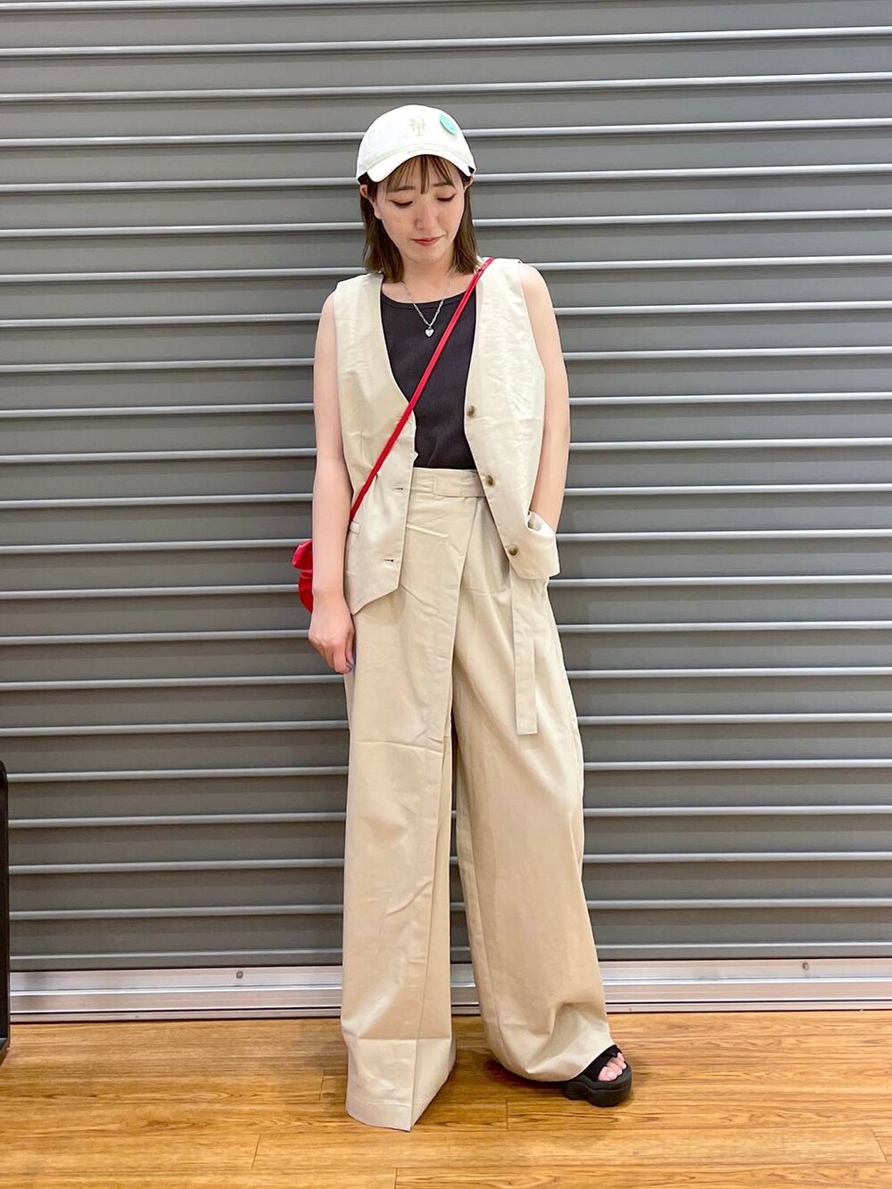 レッド系のショルダーバッグ、ホワイト系のその他パンツ、ホワイト系のベストを着用したレディースの夏コーディネートの2枚目の写真