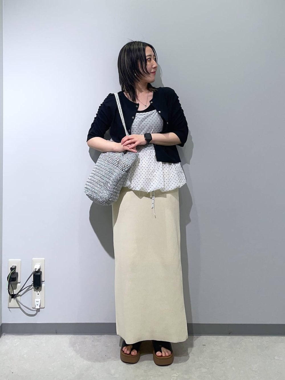 ブラック系のサンダル、ホワイト系のスカート、シルバー系のショルダーバッグを着用したレディースの春コーディネートの2枚目の写真