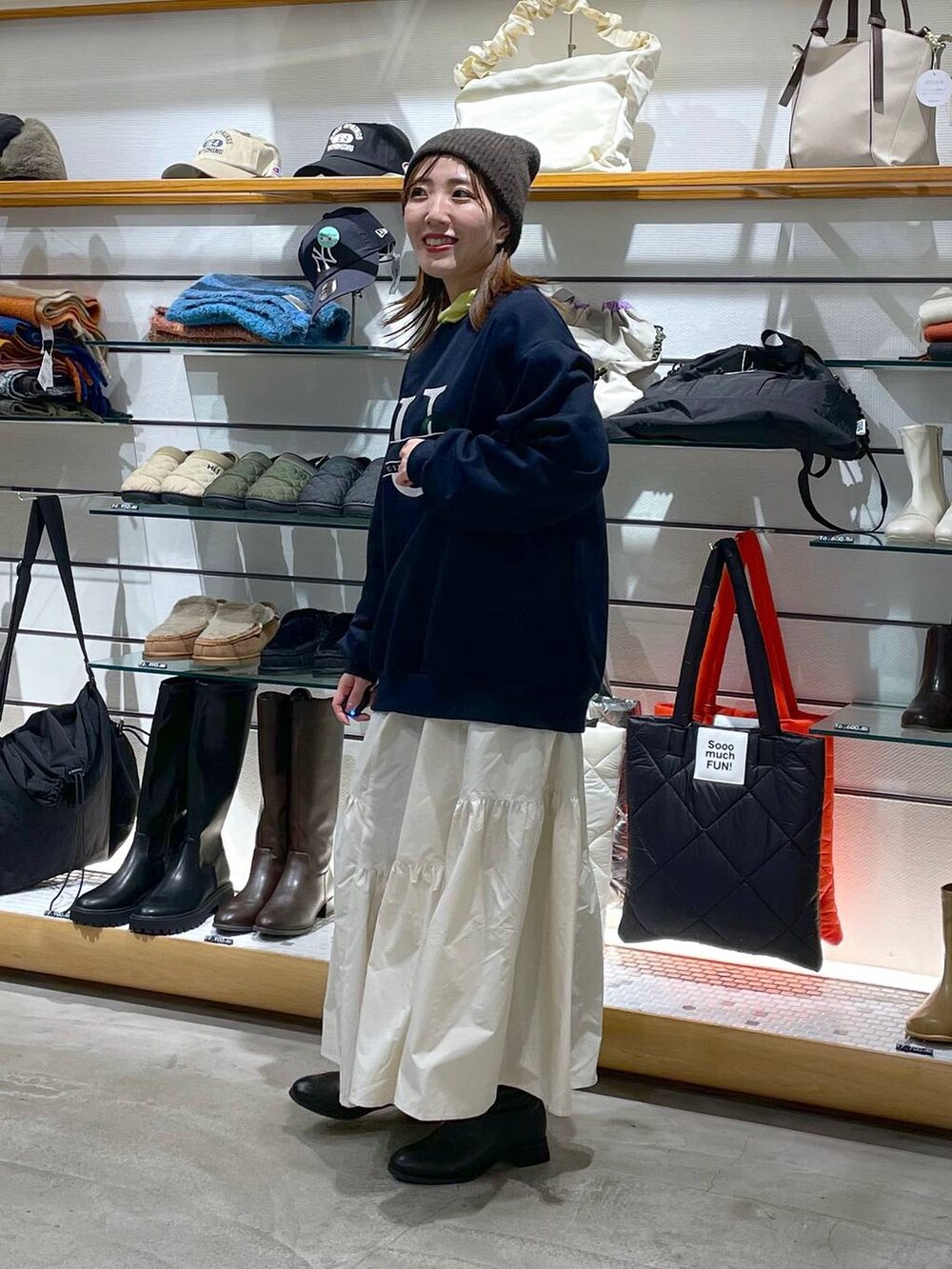 ホワイト系のスカート、ブラック系のブーツ、イエロー系のTシャツ/カットソーを着用したレディースの冬コーディネートの2枚目の写真