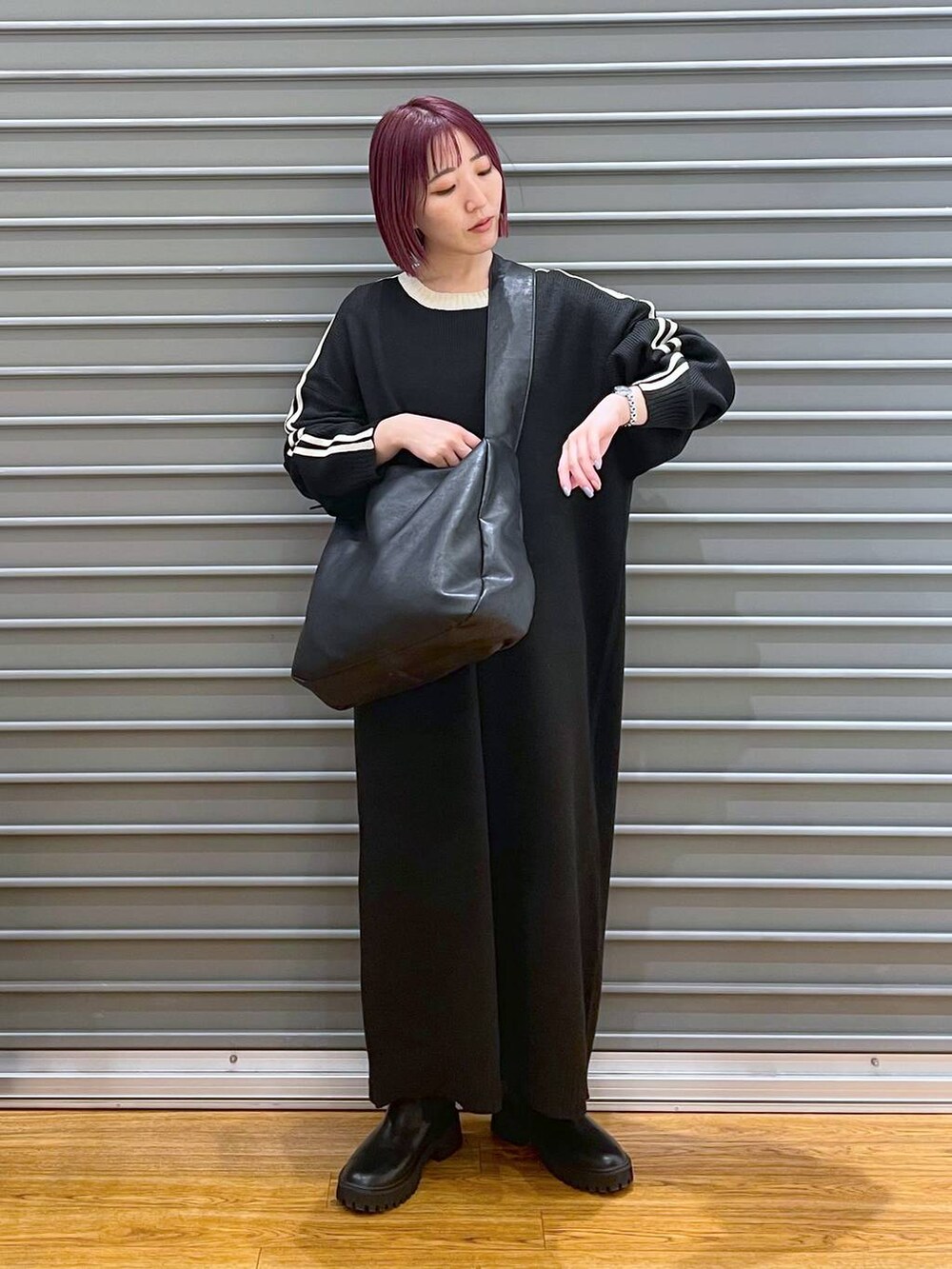 ブラック系のショルダーバッグ、ブラック系のブーツ、ブラック系のワンピースを着用したレディースの冬コーディネートの3枚目の写真