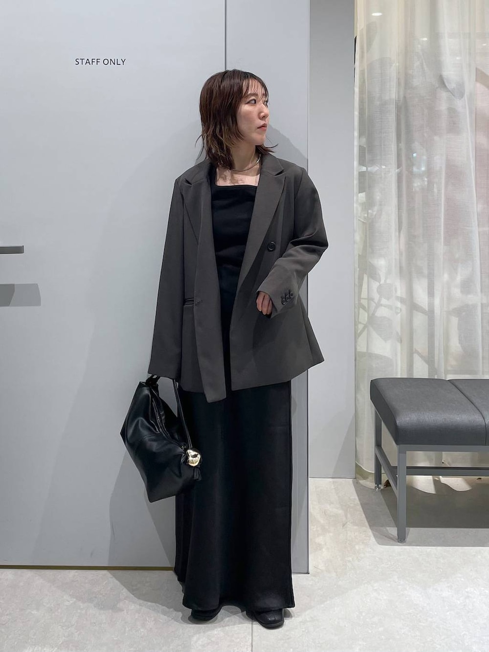 ブラック系のスカート、ブラック系のショルダーバッグ、グレー系のテーラードジャケットを着用したレディースの春コーディネートの2枚目の写真