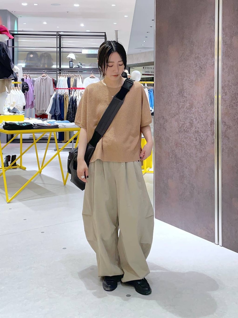グレー系のショルダーバッグ、オレンジ系のニット/セーター、ベージュ系のその他パンツを着用したレディースの春コーディネートの2枚目の写真