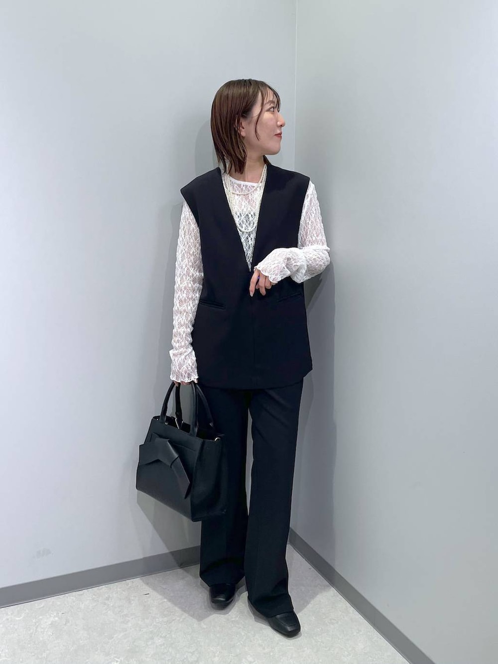 ブラック系のローファー、ブラック系のハンドバッグ、ブラック系のスーツセットを着用したレディースの冬コーディネートの2枚目の写真