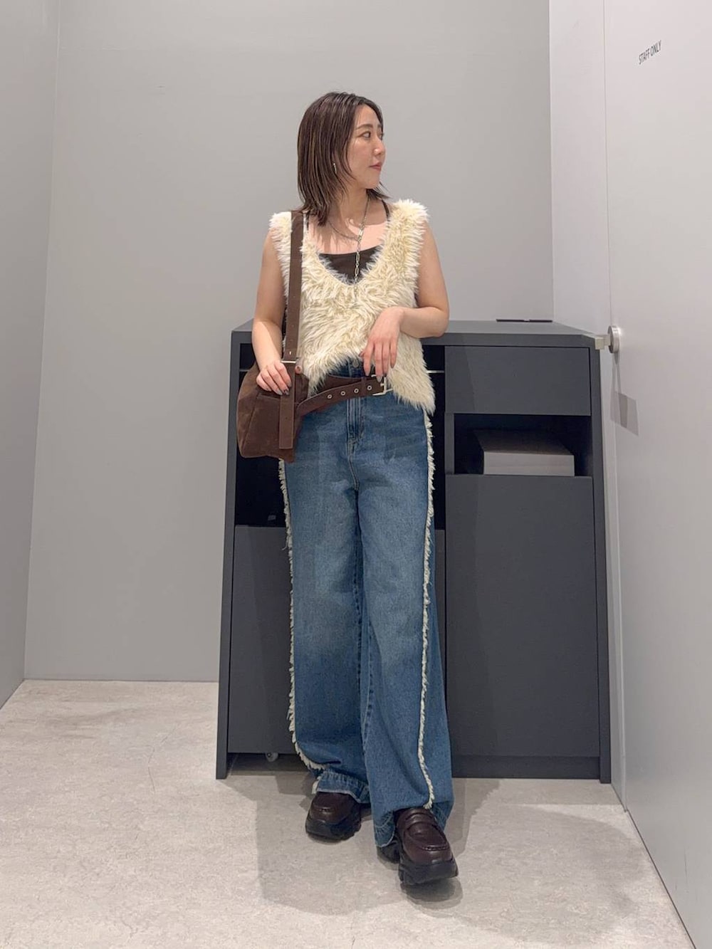 ブルー系のデニムパンツ、ベージュ系のベスト、ブラウン系のローファーを着用したレディースの夏コーディネートの2枚目の写真