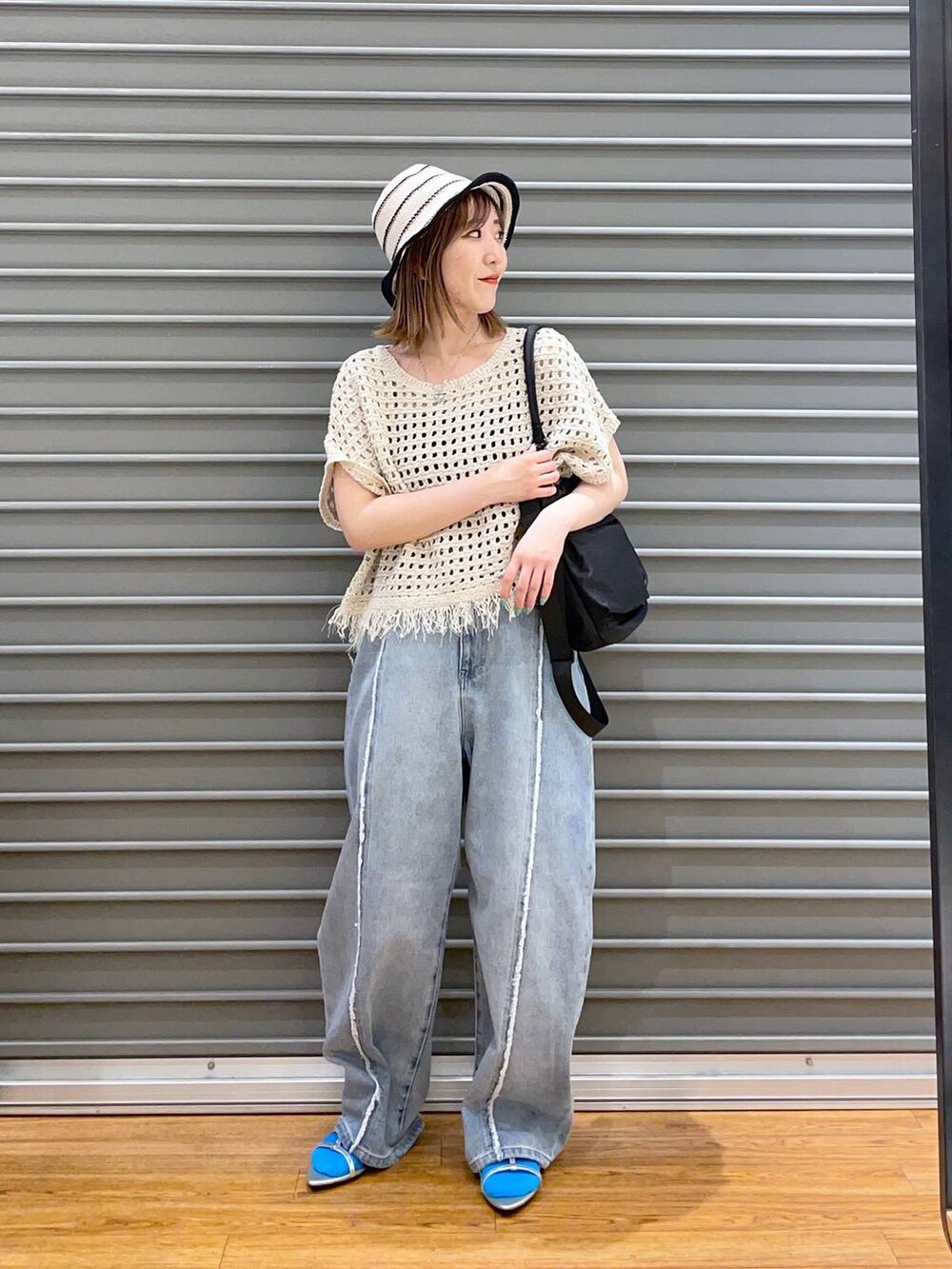 シルバー系のサンダル、ブラック系のショルダーバッグ、ブルー系のデニムパンツを着用したレディースの春コーディネートの2枚目の写真