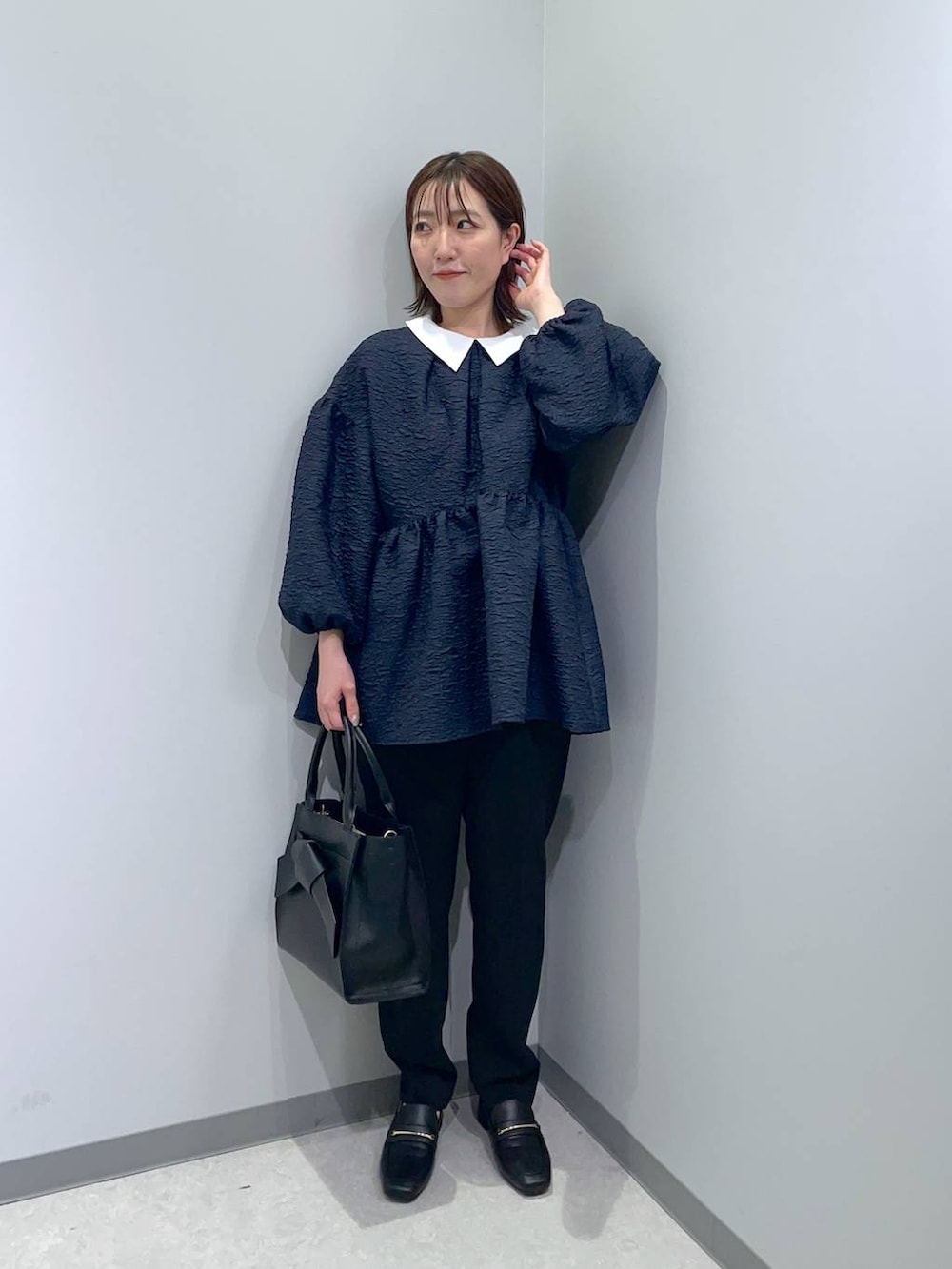 ブラック系のローファー、ブラック系のハンドバッグ、ブルー系のスーツセットを着用したレディースの冬コーディネートの2枚目の写真