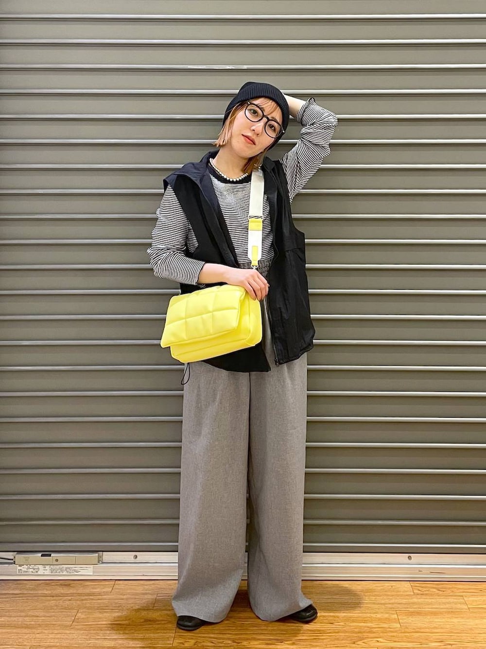 イエロー系のショルダーバッグ、ブラック系のベスト、ホワイト系のTシャツ/カットソーを着用したレディースの春コーディネートの3枚目の写真