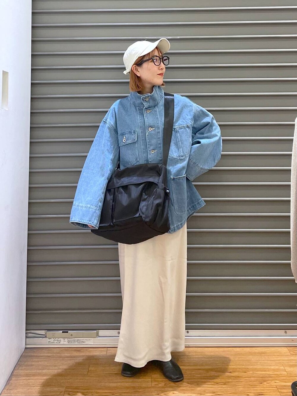 ホワイト系のスカート、ブラック系のショルダーバッグ、ブルー系のデニムジャケットを着用したレディースの春コーディネートの3枚目の写真