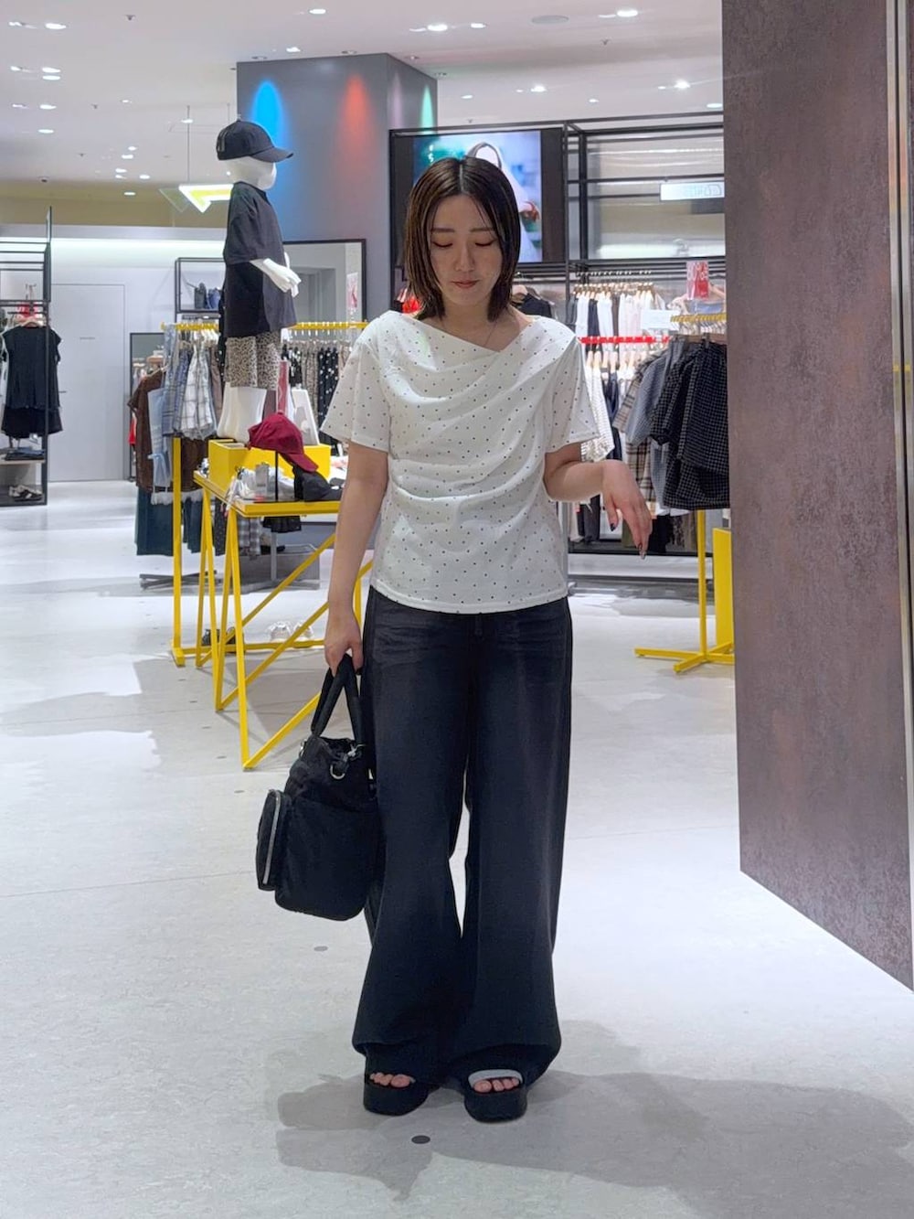 ブラック系のデニムパンツ、ベージュ系のTシャツ/カットソー、ブラック系のトートバッグを着用したレディースの夏コーディネートの2枚目の写真