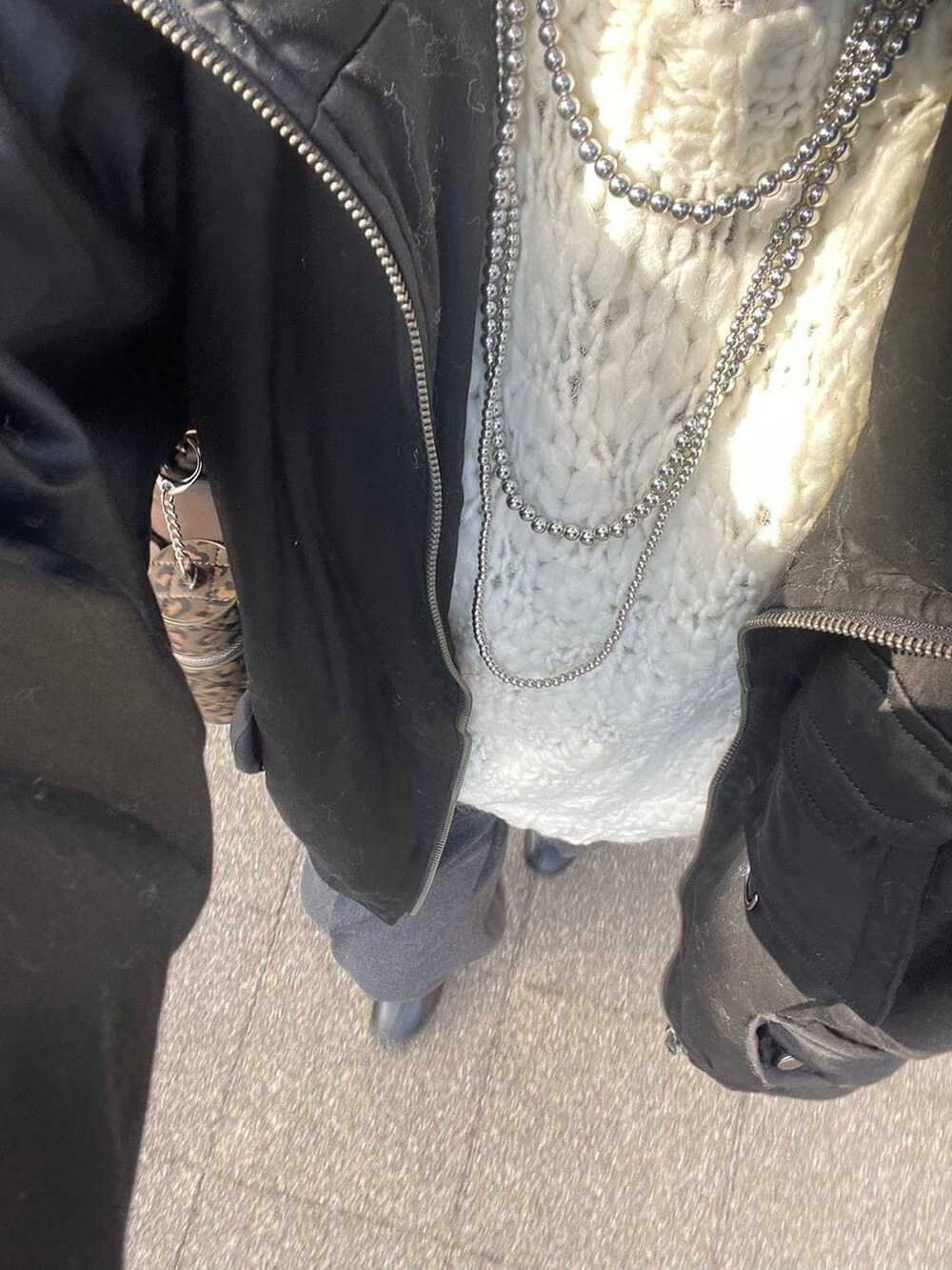 グレー系のスラックス、ブラック系のブルゾン、ホワイト系のニット/セーターを着用したレディースの冬コーディネートの2枚目の写真