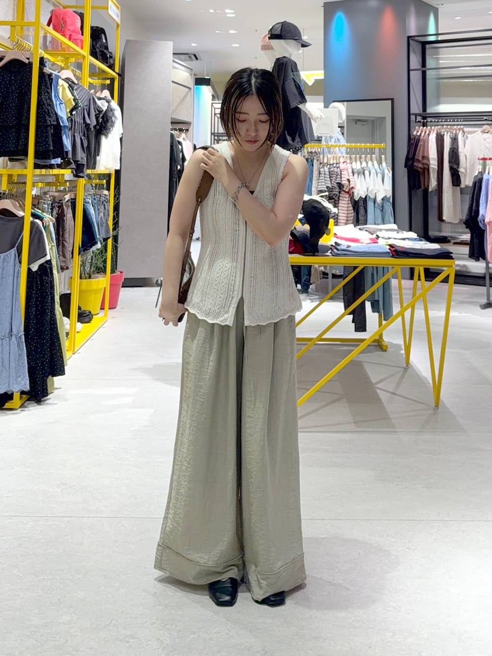 ブラウン系のショルダーバッグ、グリーン系のその他パンツ、ホワイト系のベストを着用したレディースの夏コーディネートの2枚目の写真