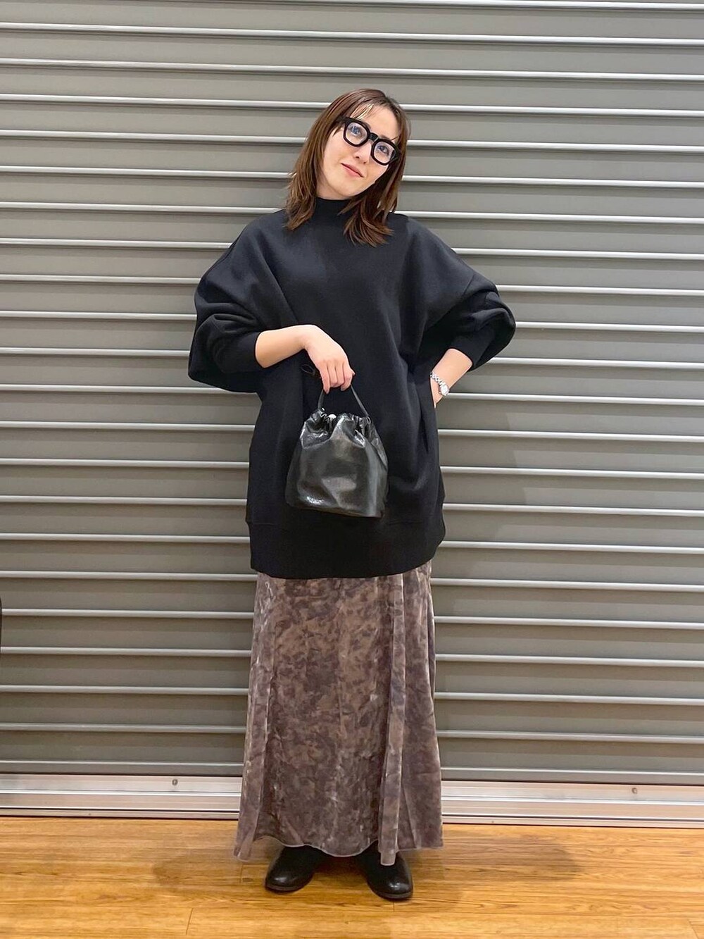 シルバー系のスカート、ブラック系のブーツ、ブラック系のチュニックを着用したレディースの冬コーディネートの2枚目の写真