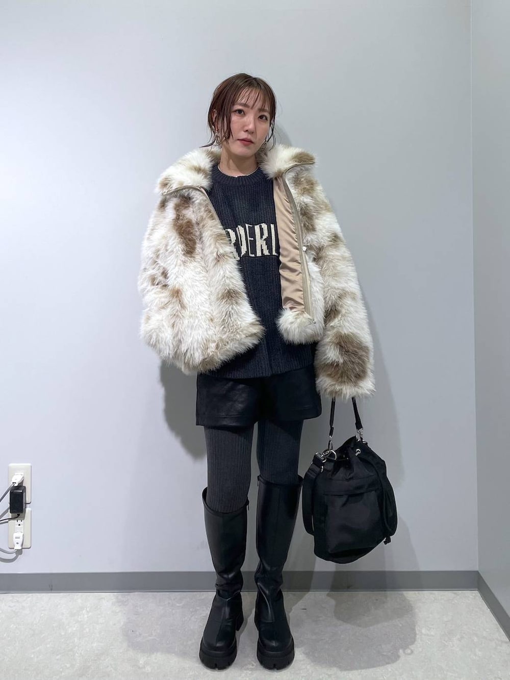 ホワイト系のブルゾン、ブラック系のショルダーバッグ、ブラック系のブーツを着用したレディースの冬コーディネートの5枚目の写真