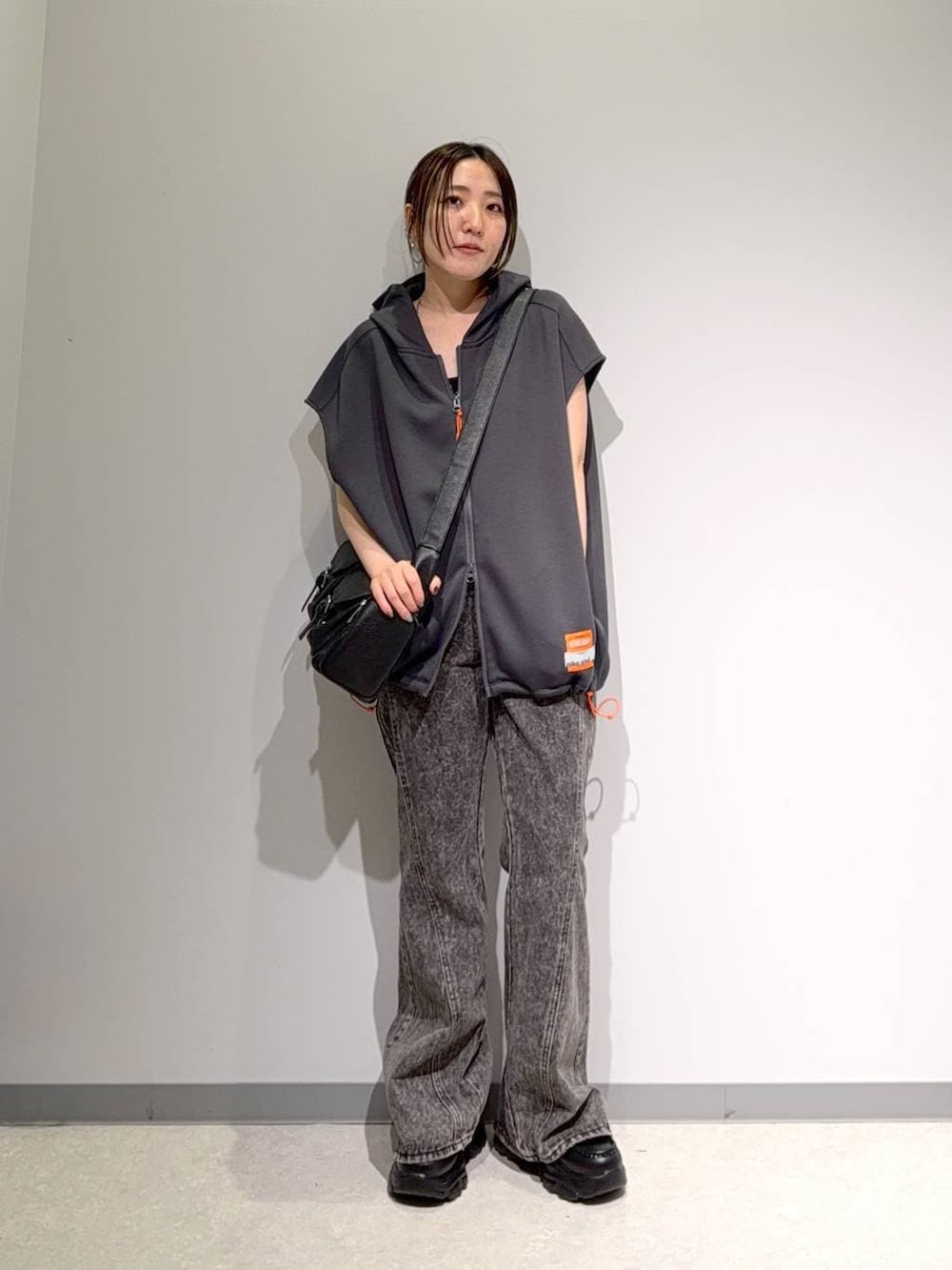 グレー系のベスト、ブラック系のデニムパンツ、ブラック系のショルダーバッグを着用したレディースの夏コーディネートの2枚目の写真