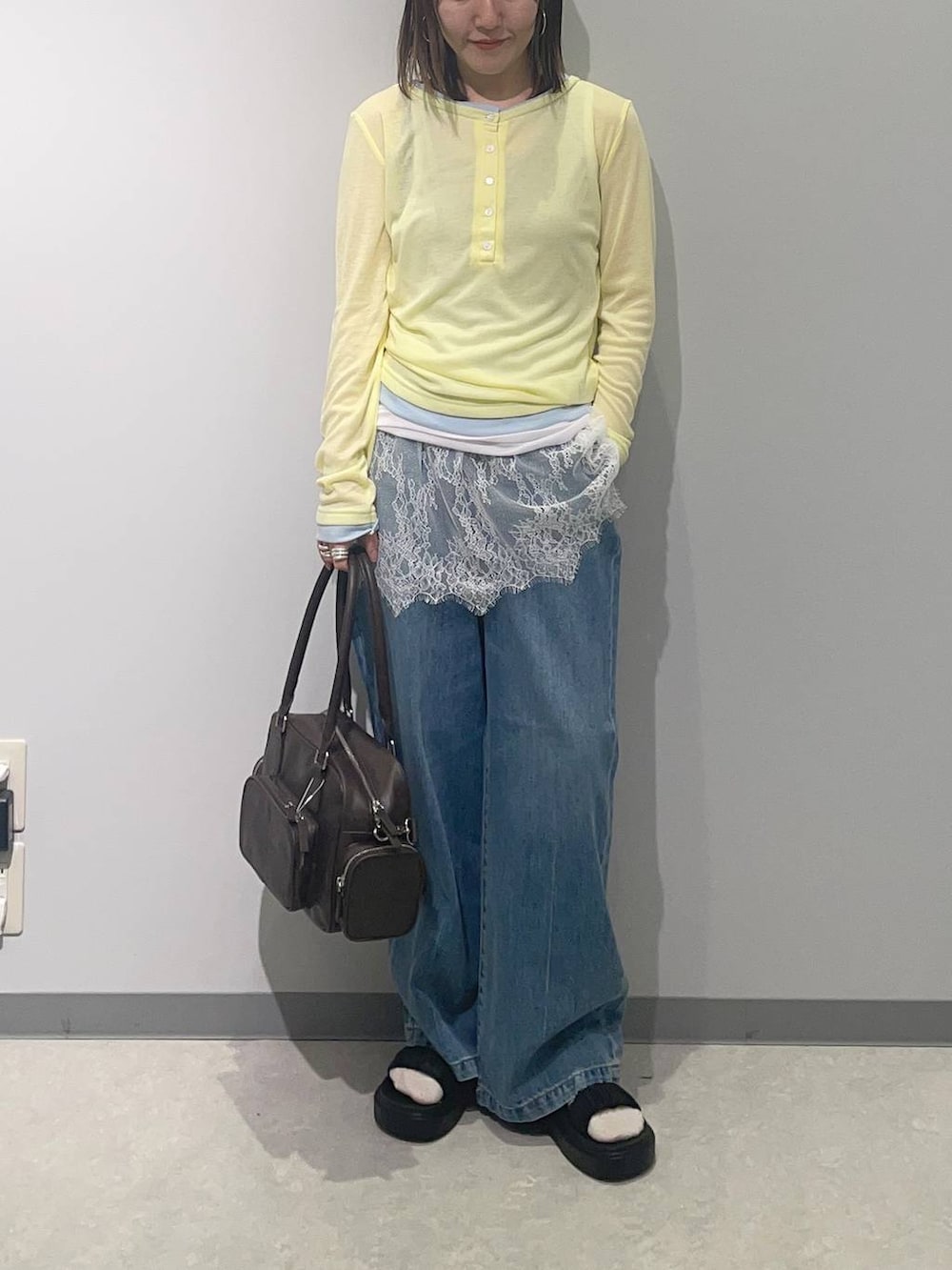 ブルー系のデニムパンツ、ブラウン系のボストンバッグ、ブラック系のサンダルを着用したレディースの春コーディネートの2枚目の写真