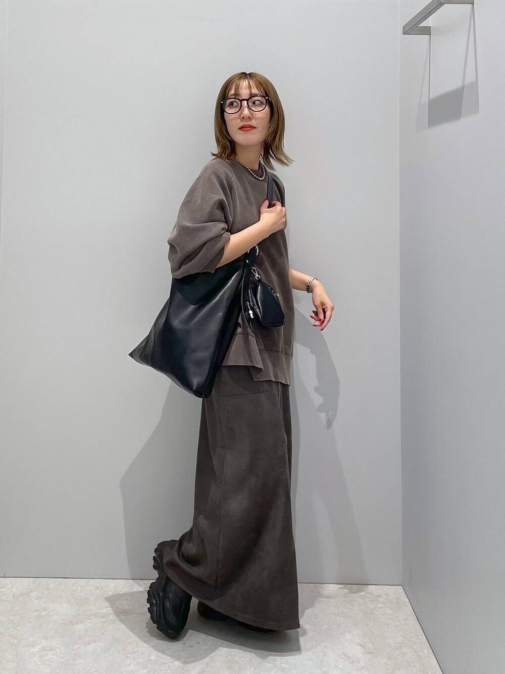 ブラック系のショルダーバッグ、ブラック系のスウェット、グレー系のスカートを着用したレディースの秋コーディネートの2枚目の写真