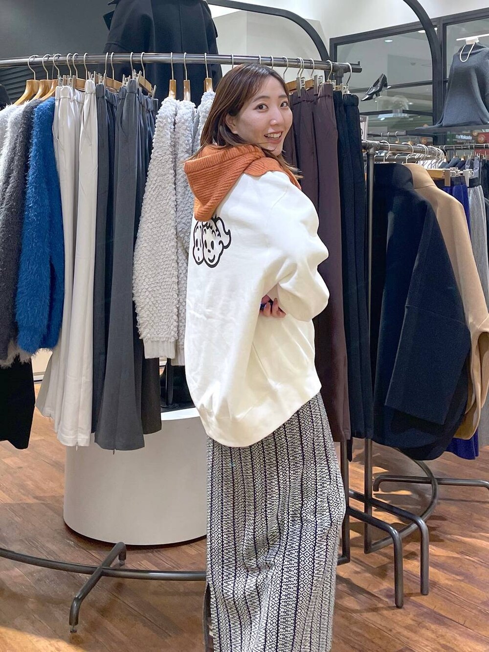 ブラック系のスカート、ホワイト系のスウェット、オレンジ系のネックウォーマー/スヌードを着用したレディースの冬コーディネートの3枚目の写真