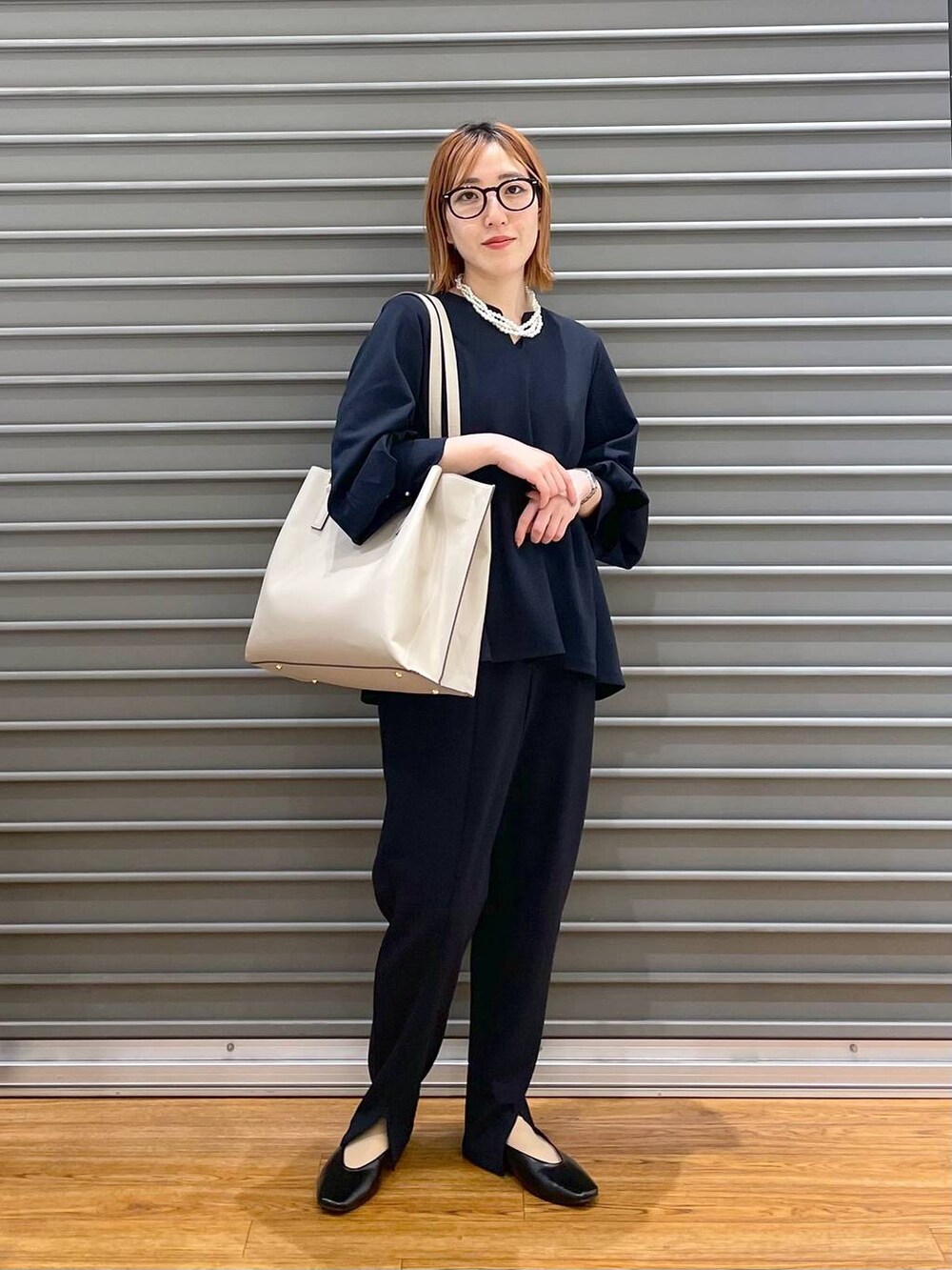 ブラック系のパンプス、ブルー系のスラックス、ベージュ系のトートバッグを着用したレディースの冬コーディネートの2枚目の写真