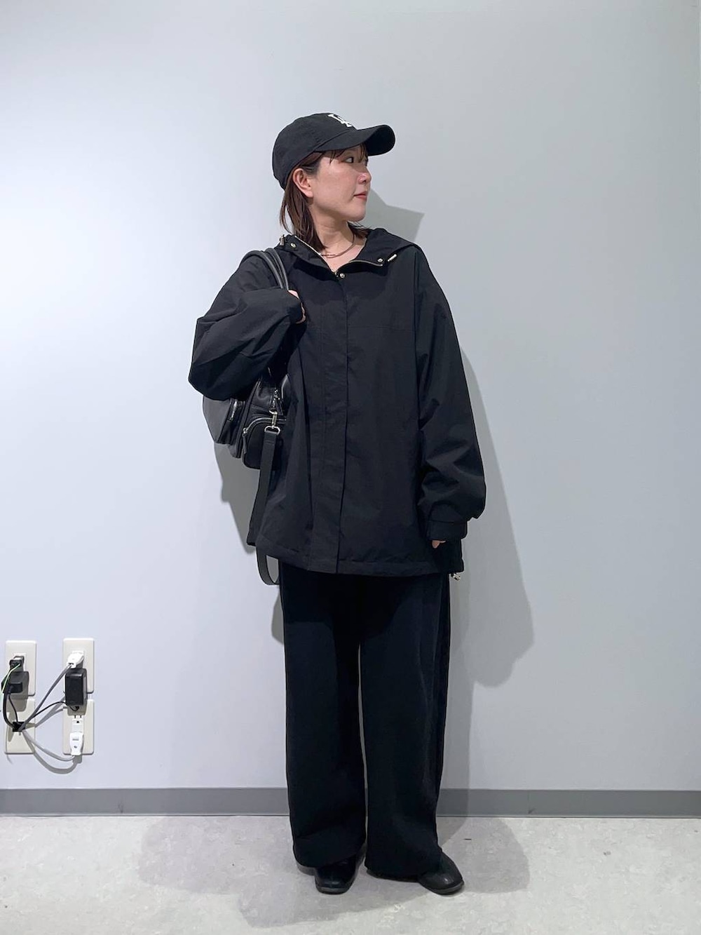 ブラック系のマウンテンパーカー、ブラック系のボストンバッグ、ブラック系のTシャツ/カットソーを着用したレディースの冬コーディネートの2枚目の写真