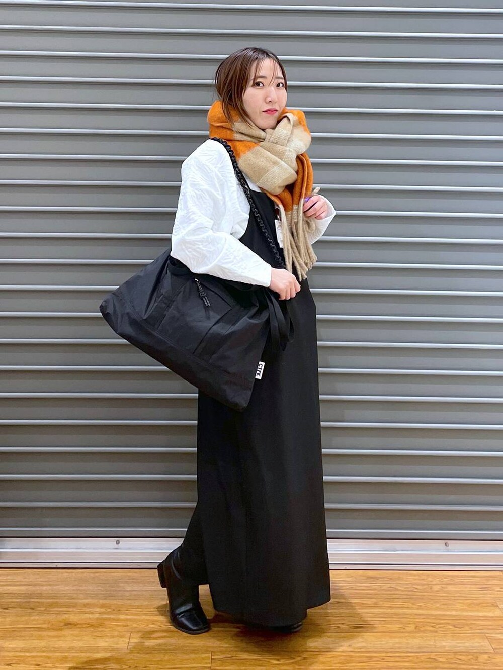 ブラック系のワンピース、ブラック系のショルダーバッグ、ホワイト系のTシャツ/カットソーを着用したレディースの冬コーディネートの3枚目の写真